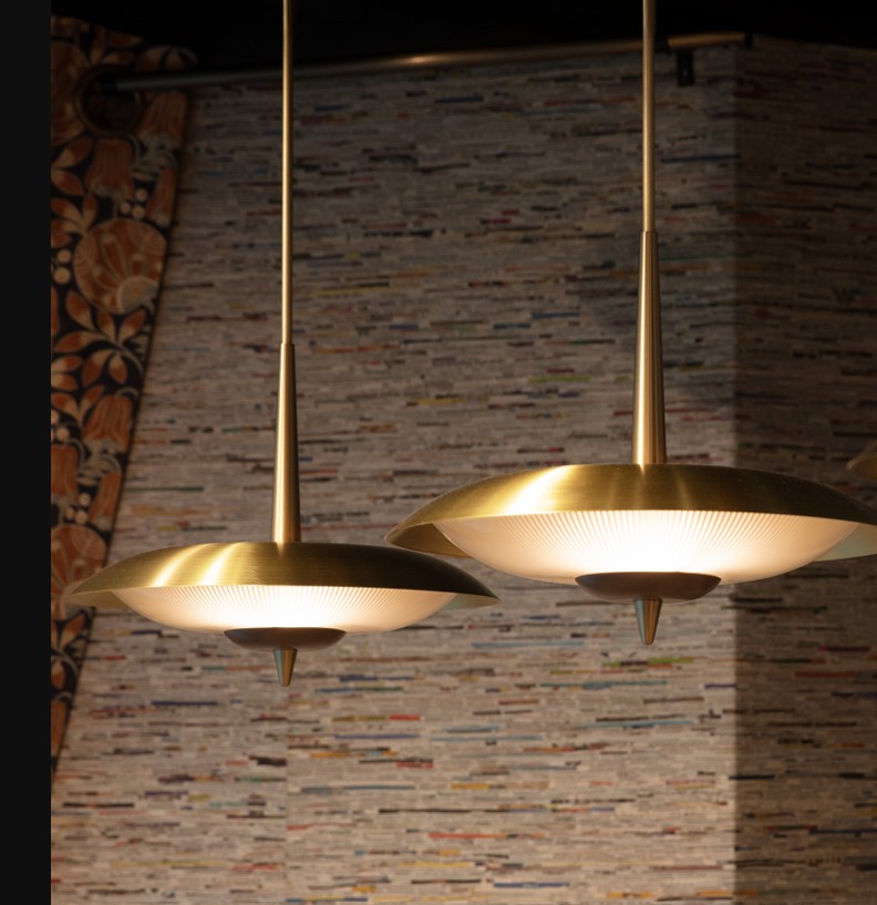 Two modern pendant lights with gold and black shades hang from the ceiling, against a textured stone wall background.