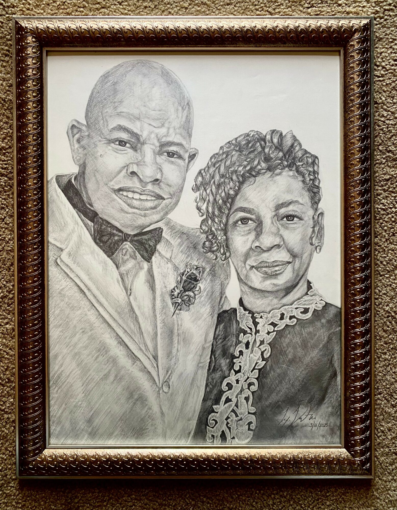 Black and white portrait of a smiling man and woman dressed formally, framed on a wall.