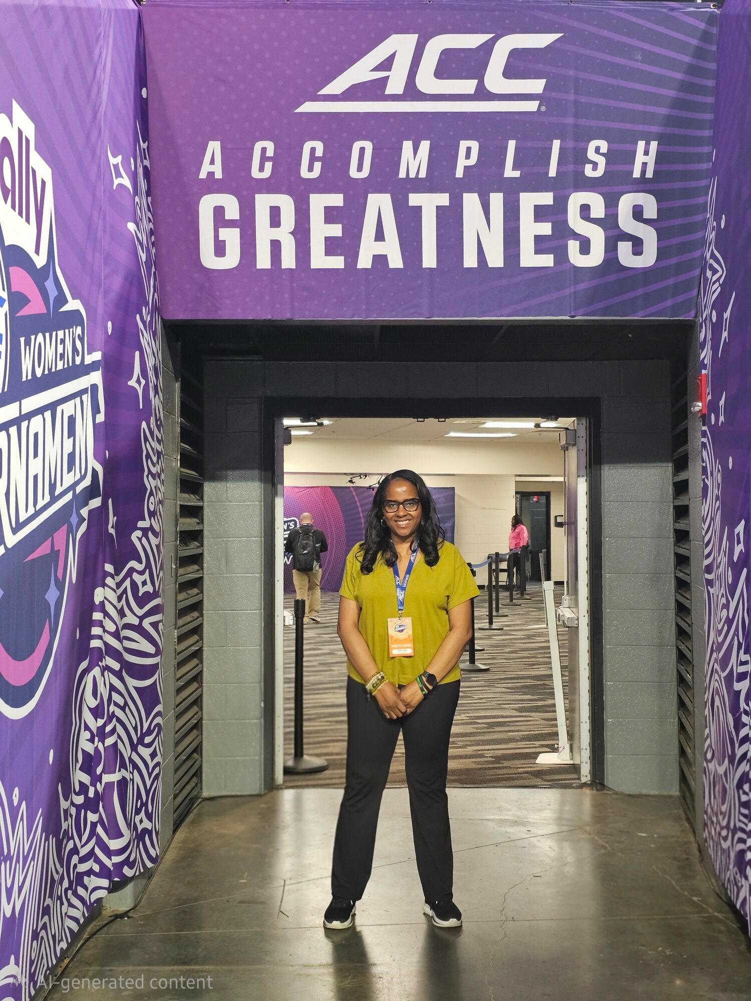 Young woman standing in front of entrance with purple ACC banners, smiling, wearing yellow shirt and black pants.