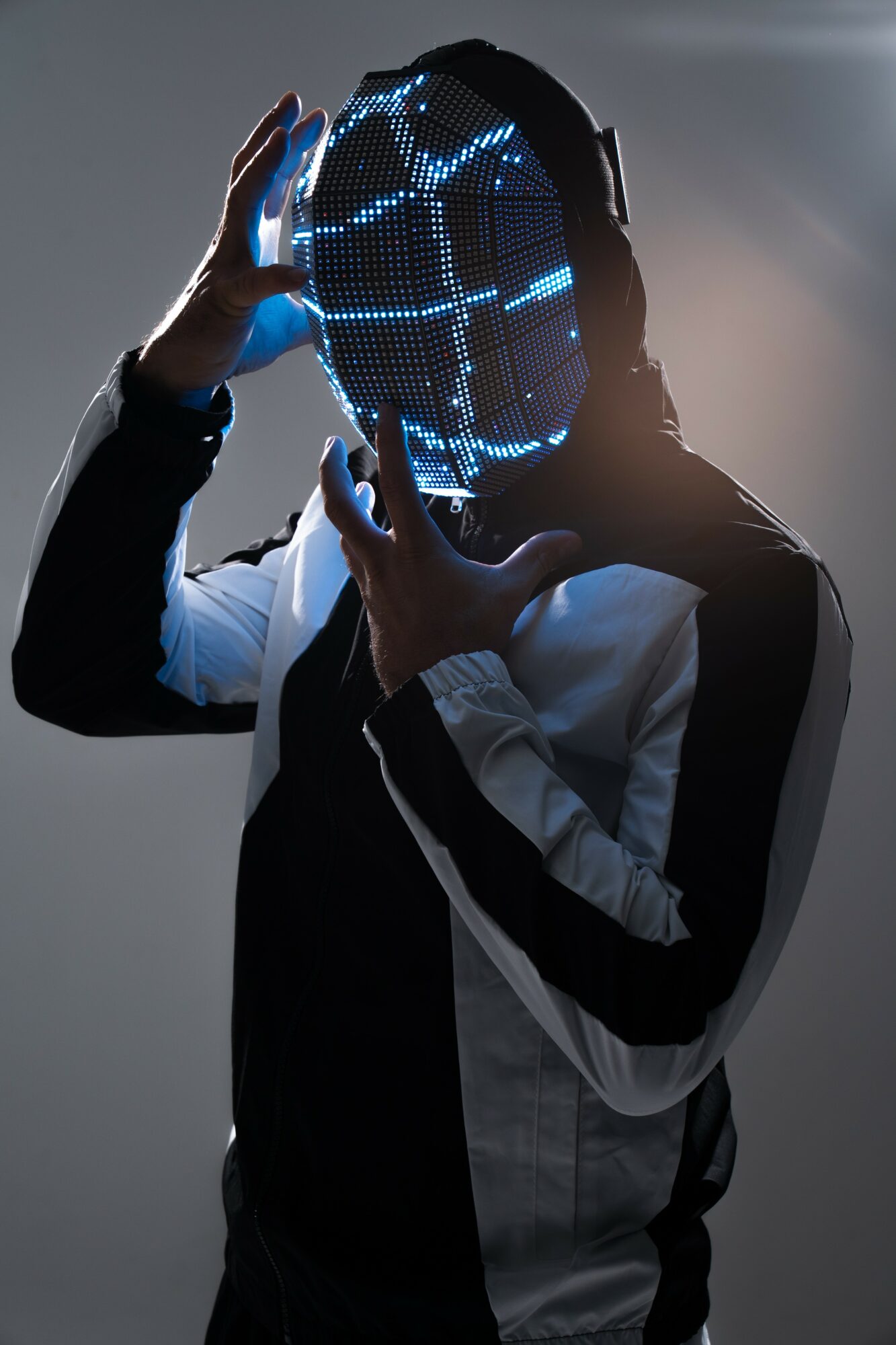 Person holding a glowing, digital, circular mask in front of face, with a dark background.