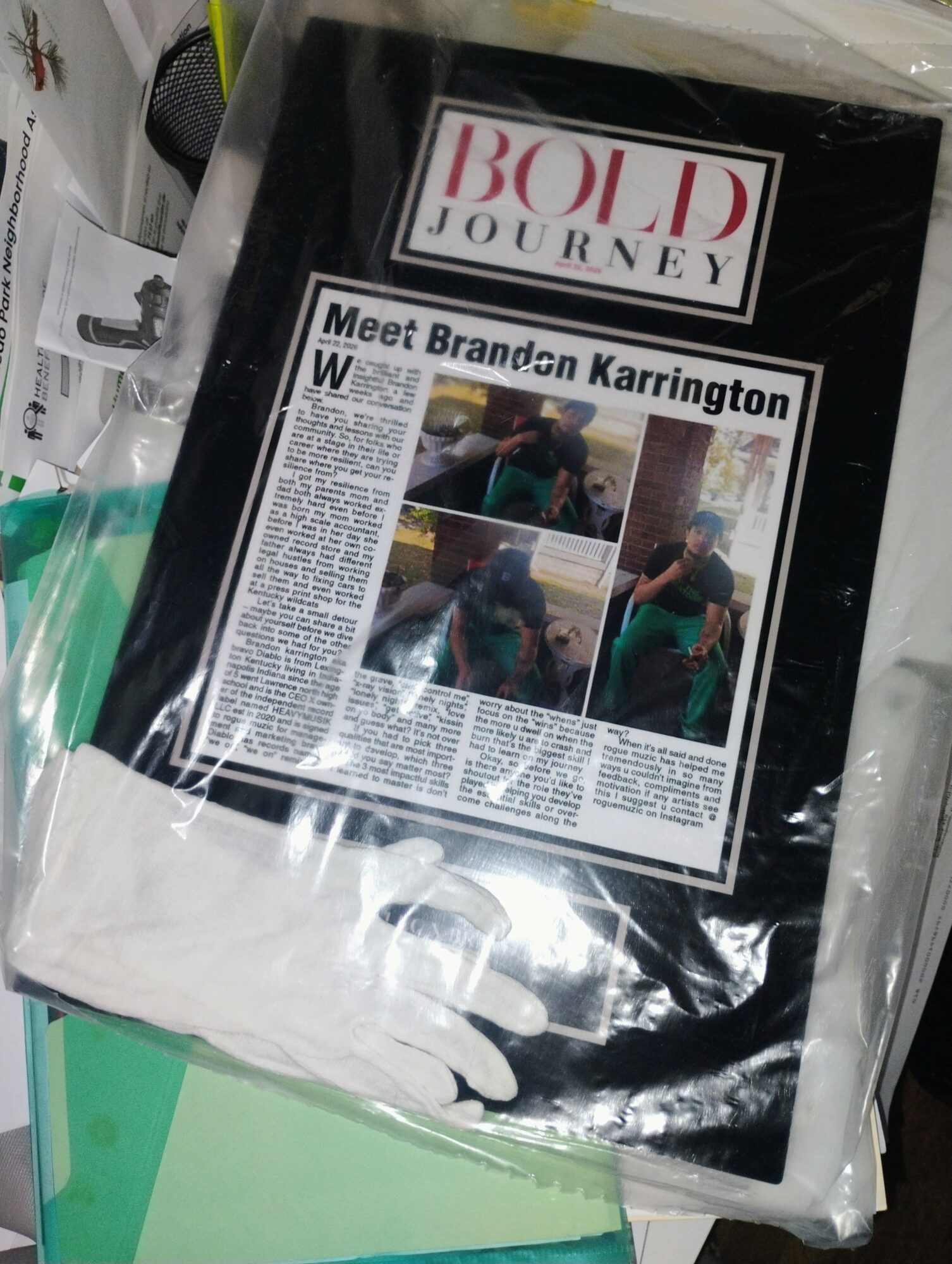 A magazine titled 'BOLD JOURNEY' with a newspaper article about Brandon Karrington and four photos, lying on a surface.