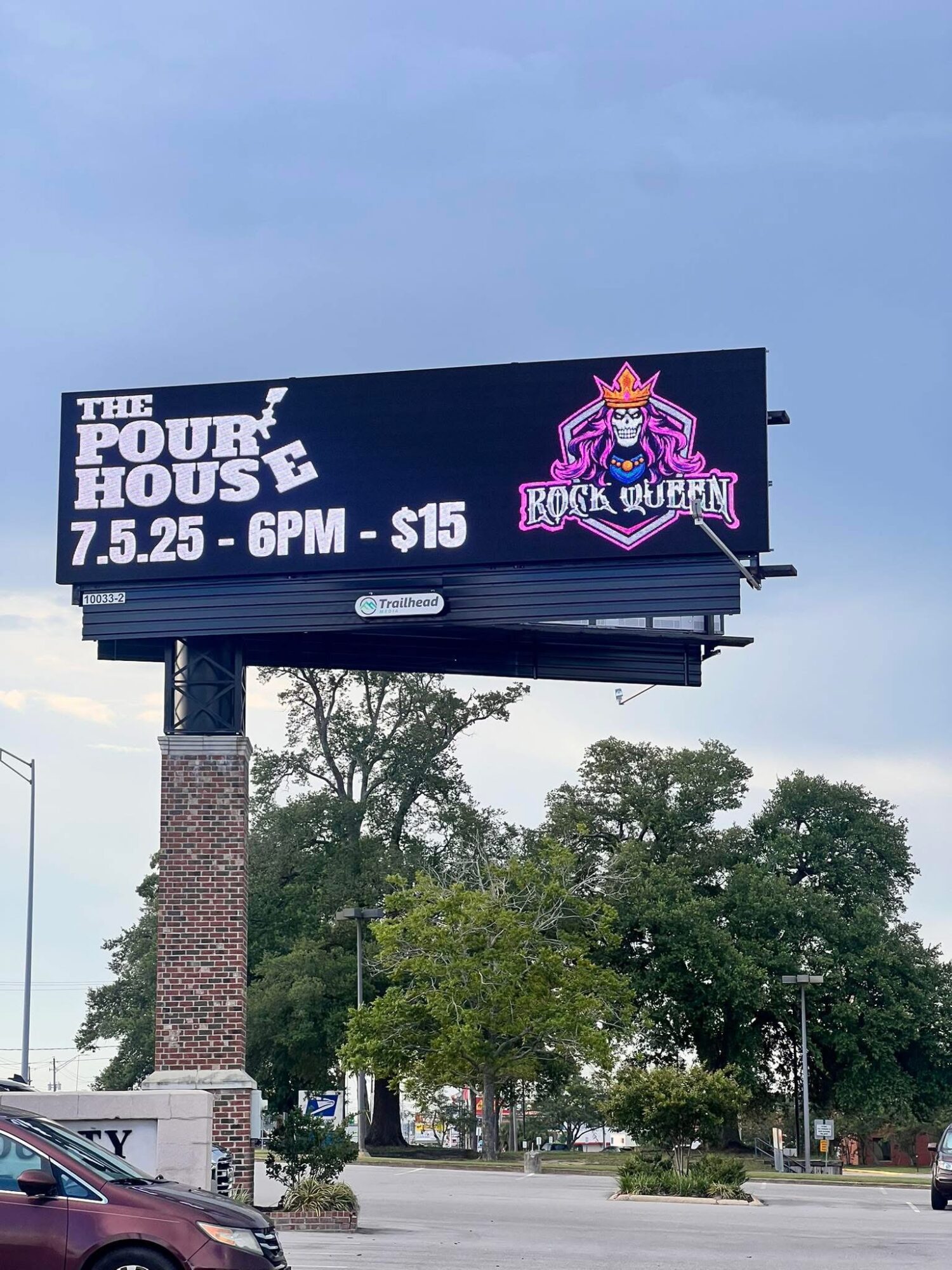Billboard advertising a rock show event with a purple and pink logo, event details, and a blue sky background.