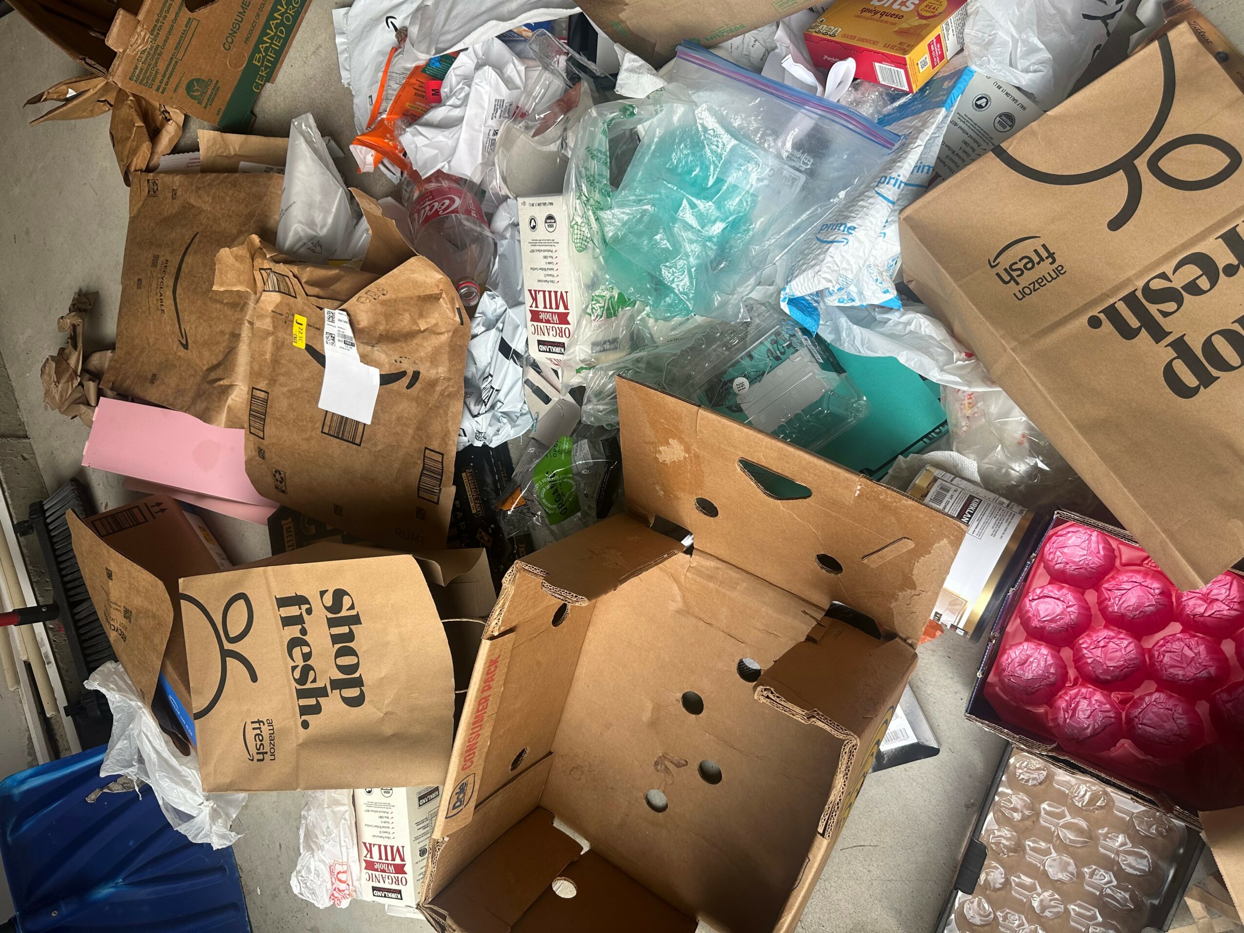 Pile of assorted cardboard boxes, plastic bags, and packaging materials in a cluttered space.