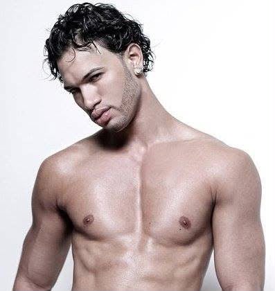Young man with curly dark hair and light skin, shirtless, looking at the camera, against a plain white background.