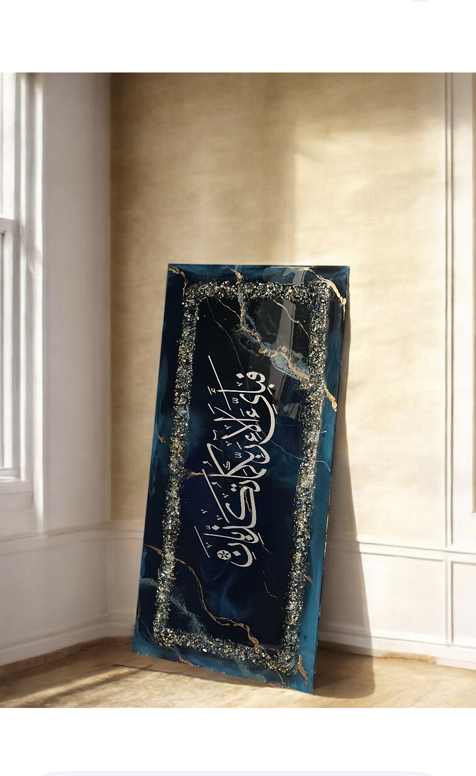 A decorated blackboard with gold and white writing and designs, leaning against a wall near a window, in a room with wooden floor.