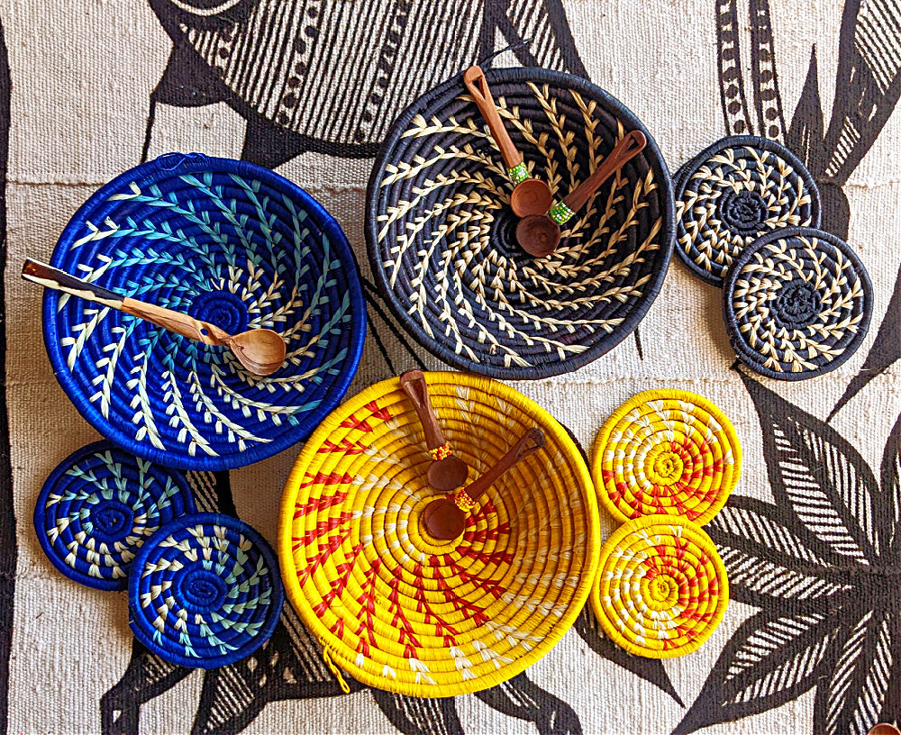 Colorful woven baskets and spoons arranged on a patterned surface, with black, white, and gray design elements.