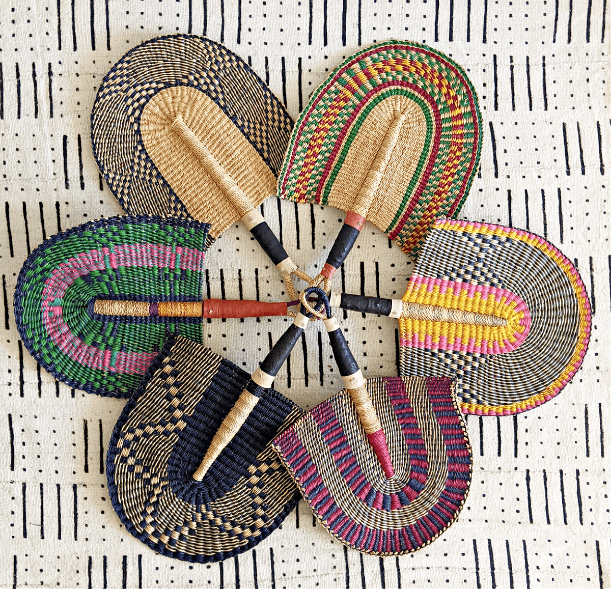 Six beaded hair accessories arranged in a circle on a striped fabric background.