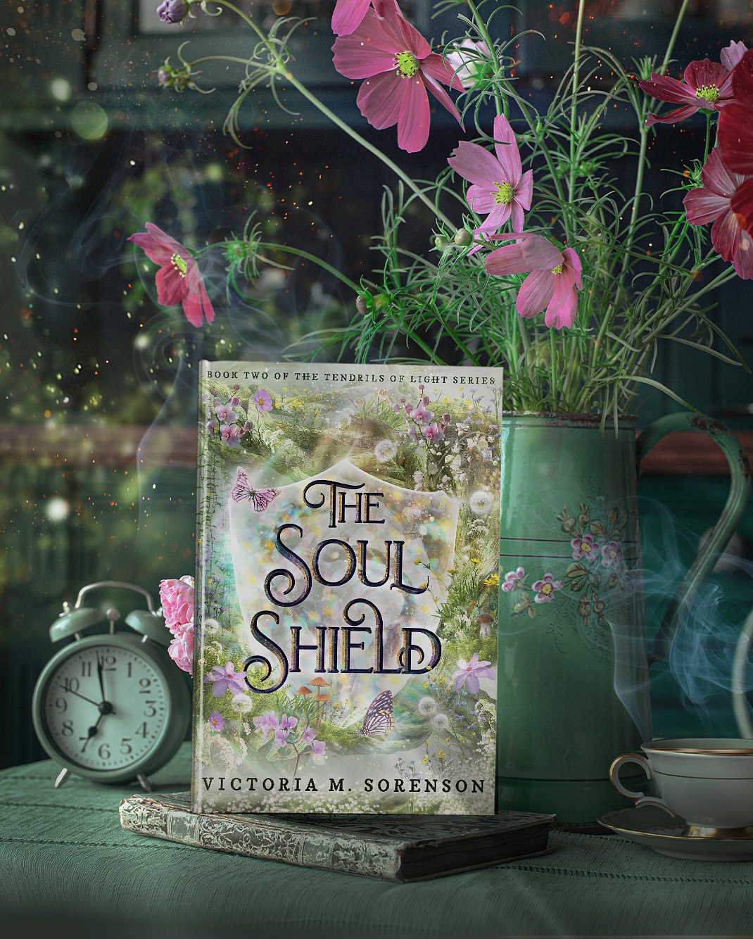 Book titled 'The Soul Shield' by Victoria M. Sorenson on a table with pink flowers, a clock, and a teacup.