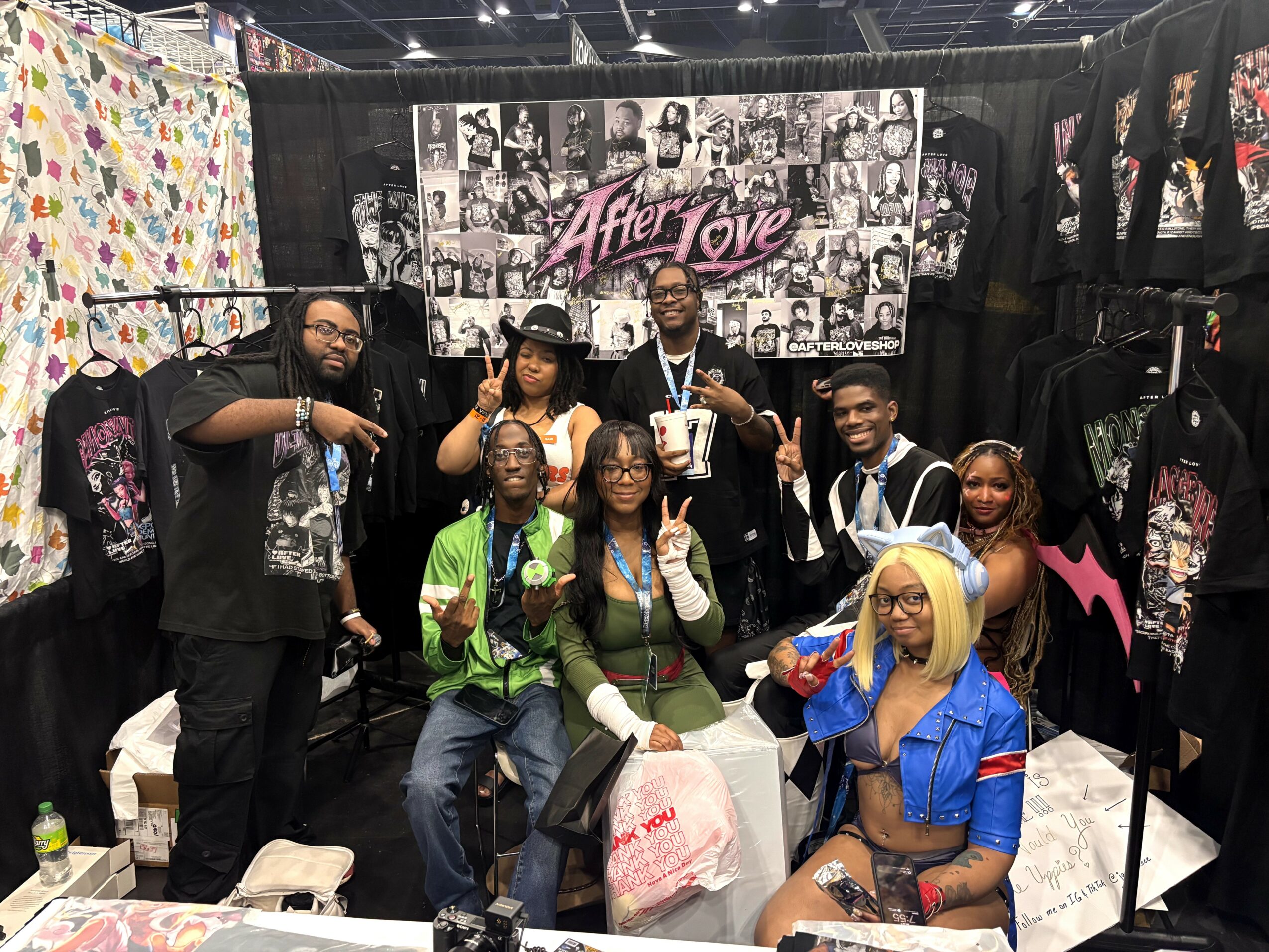 Group of eight people posing at a booth with clothing and a banner reading 'After Love.'