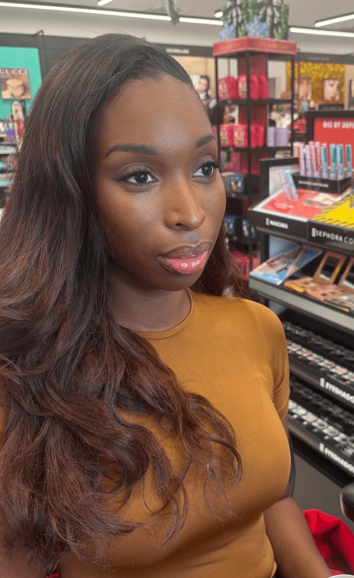 Young woman with long wavy hair and makeup in a store aisle with makeup products and displays