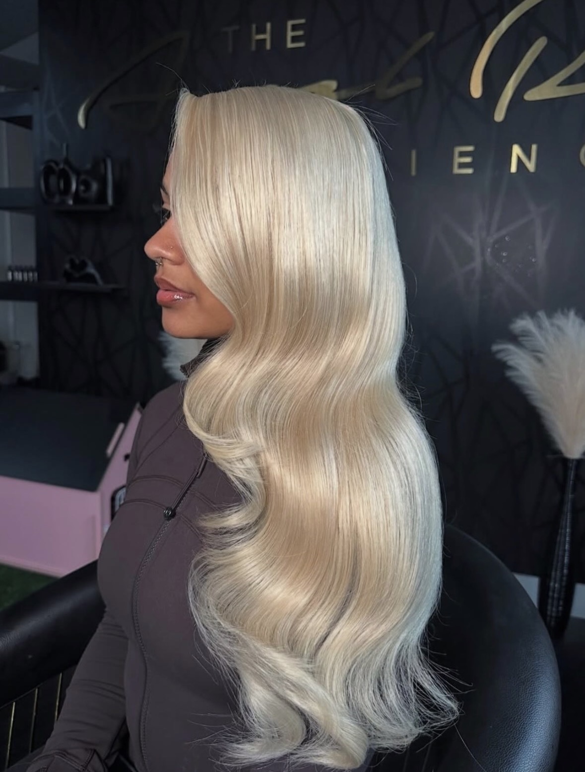Side view of a woman with long, wavy, platinum blonde hair in a salon setting.