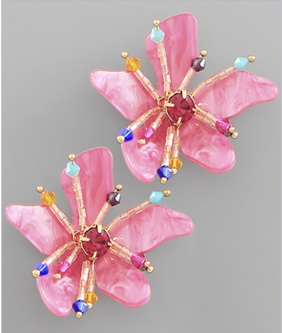 Two pink flower-shaped decorative objects with colorful beads and gold accents on a gray background.