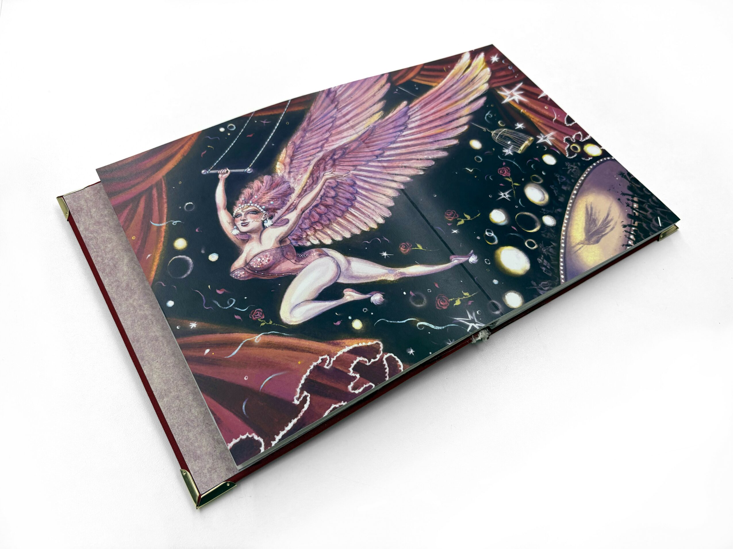 Open book with colorful fantasy illustration of a winged creature in space, stars, planets, and cosmic elements, on a white background.