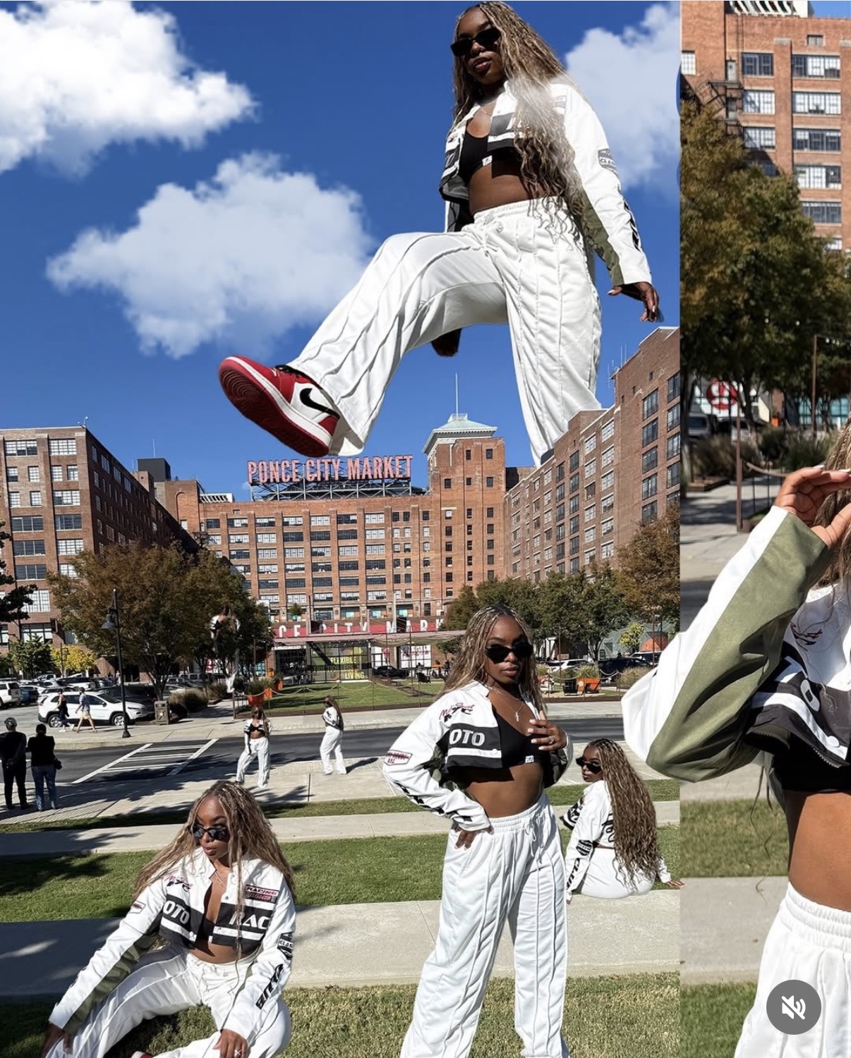 A woman in white pants and a black top jumps in an urban park with buildings and trees behind her.