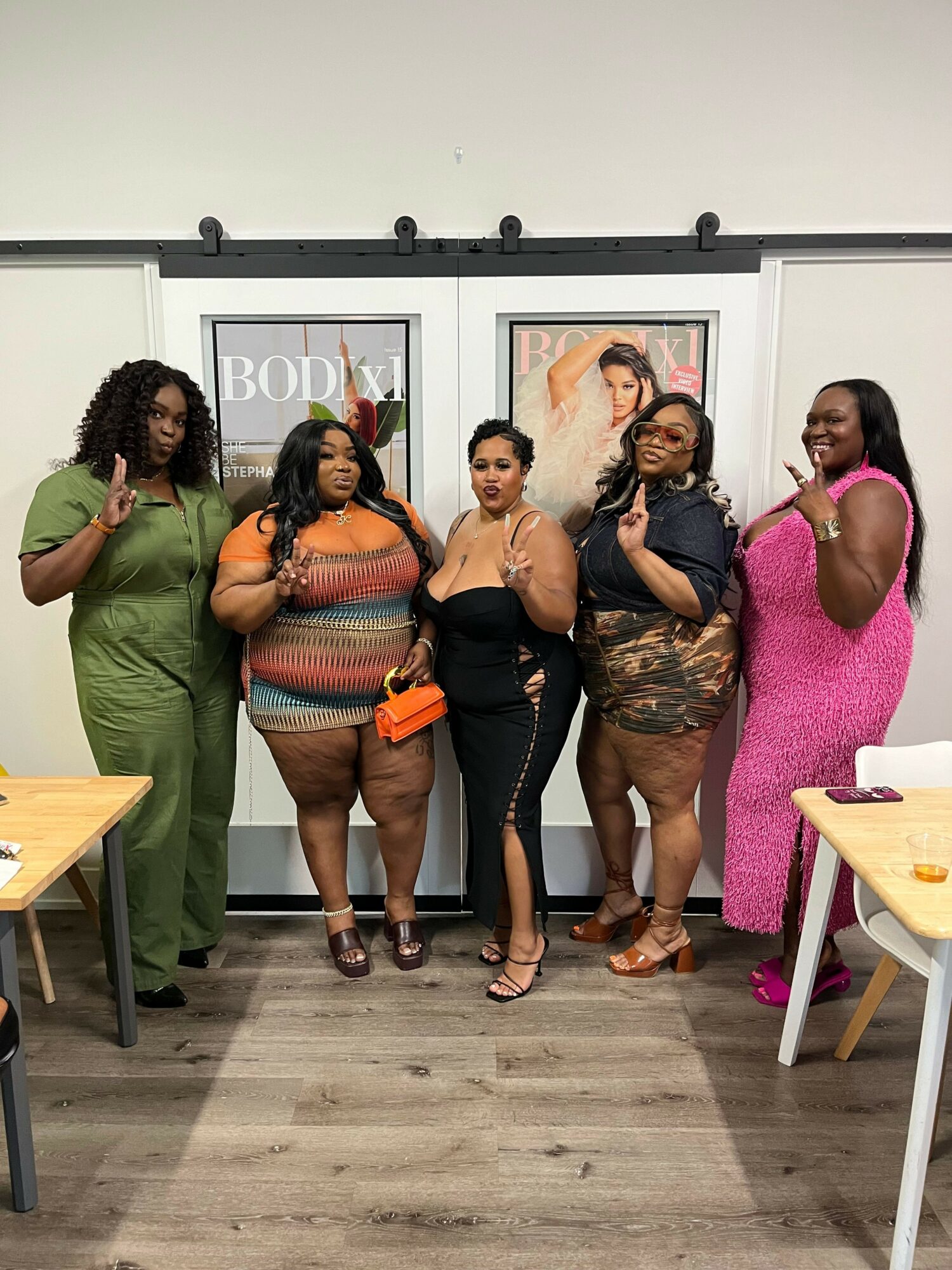 Five women standing together in an art gallery, posing for a photo, with framed artwork on the wall behind them.