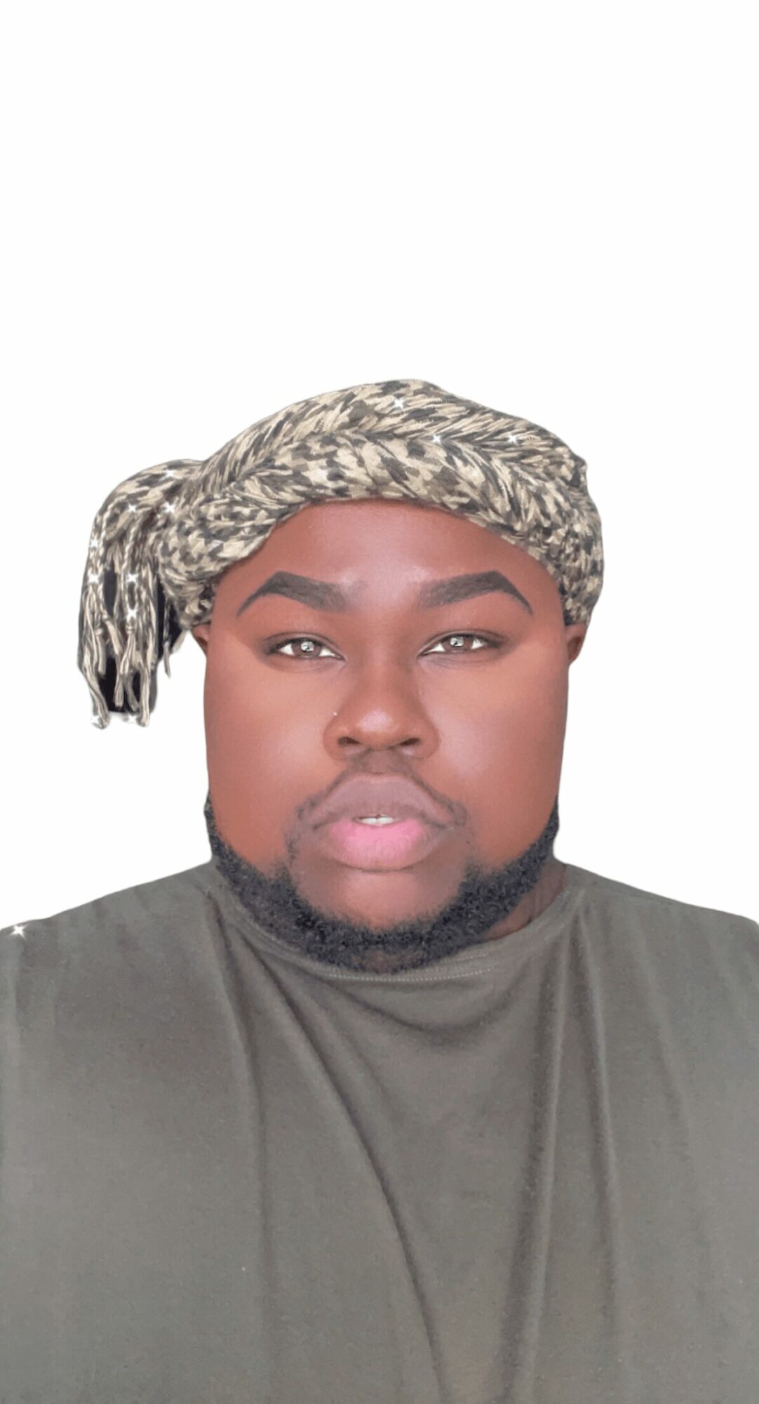 Person with a patterned headscarf, wearing a dark shirt, looking directly at the camera, neutral background.