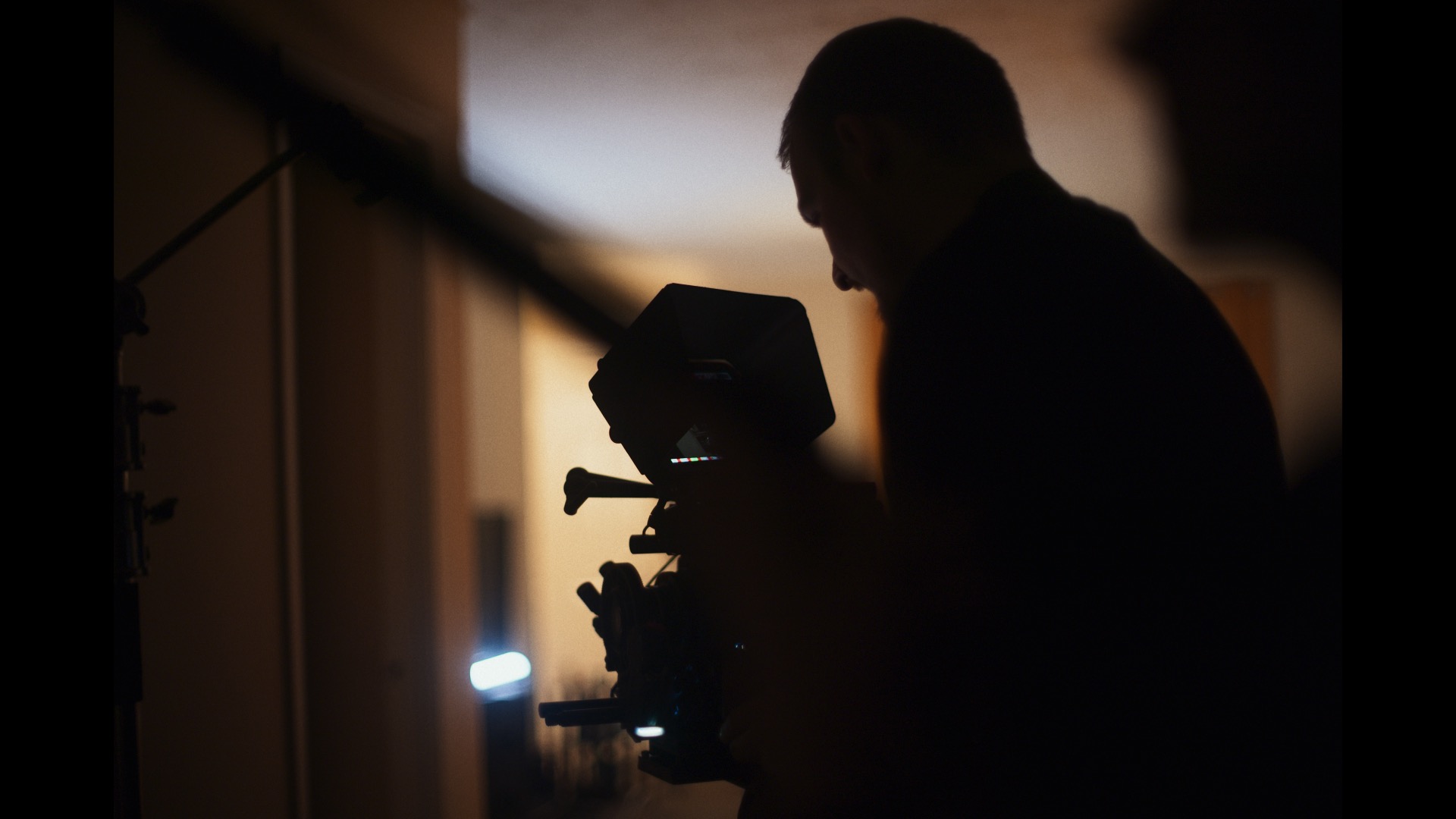 Silhouette of a person operating a camera in a dimly lit room.