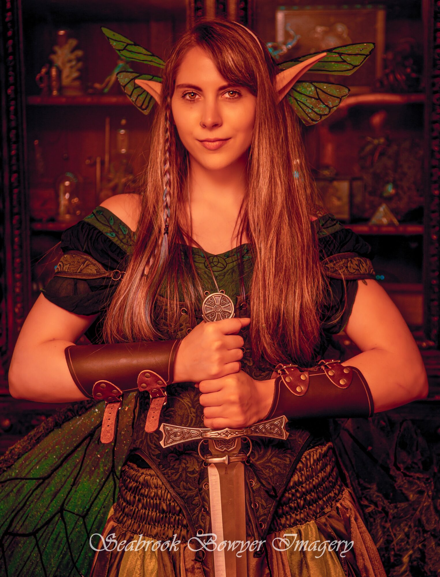 Young woman with long hair dressed as a fantasy elf, wearing leaf-like accessories and holding a sword, in a dimly lit room.