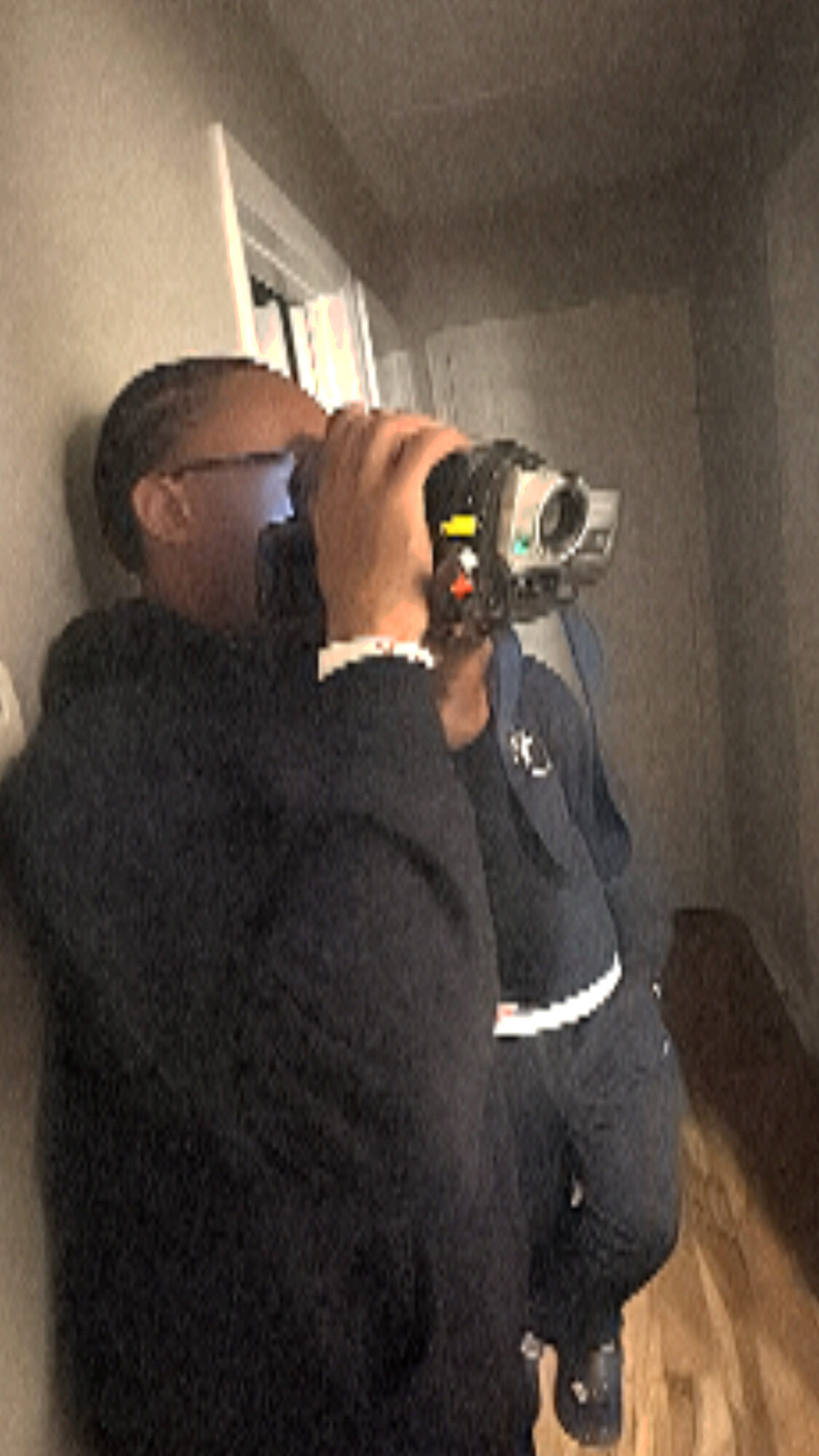 Person taking a photo with a camera, facing a mirror in a dimly lit room.