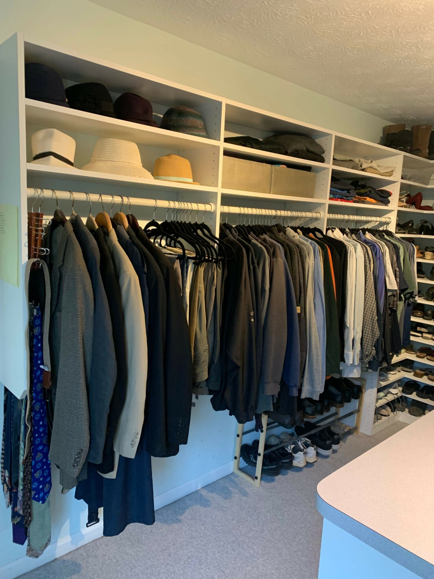 Closet with shelves holding shoes, folded clothes, and hanging garments, organized neatly. Floor visible at the bottom.