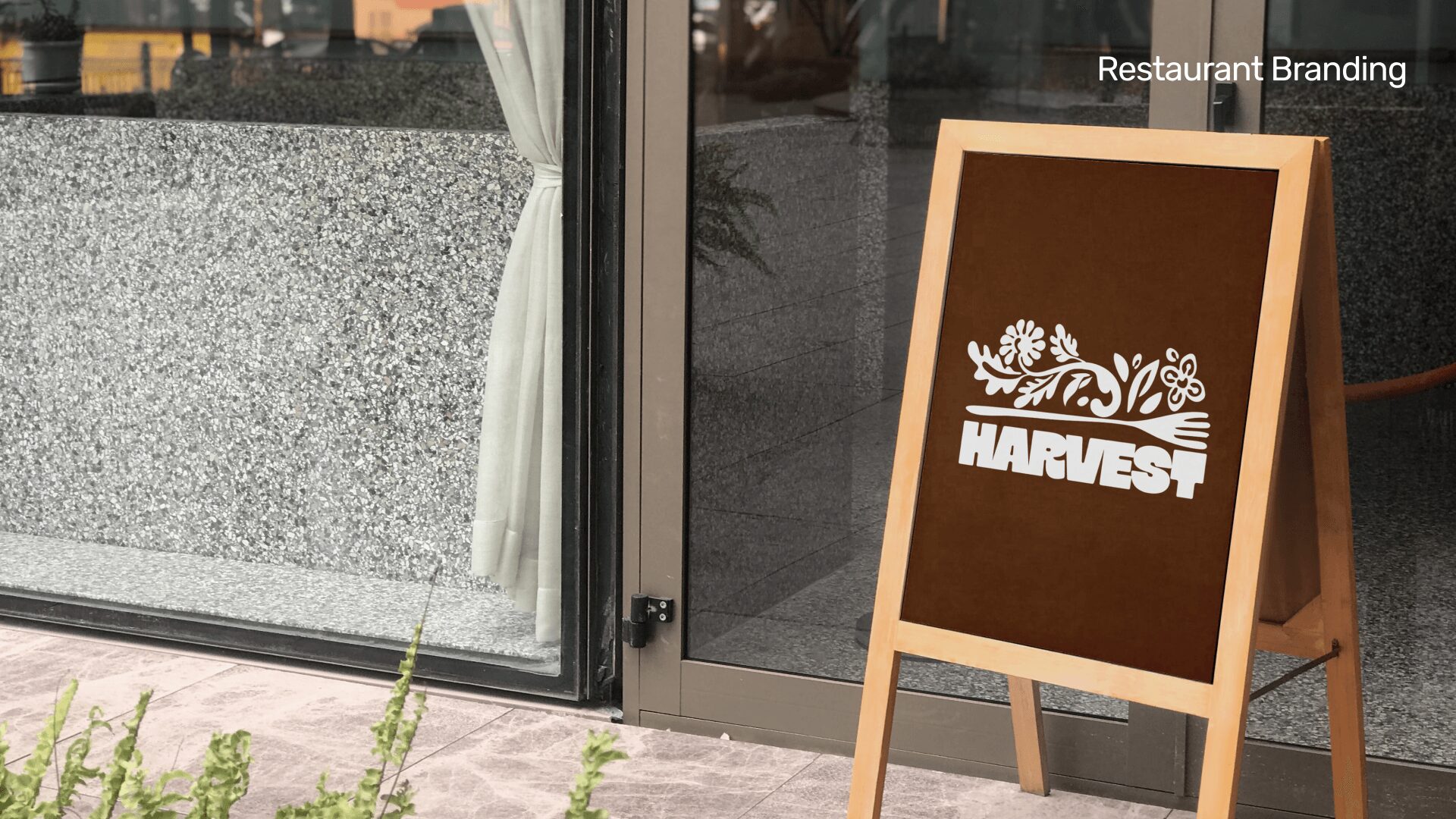 A brown sandwich board sign outside a restaurant with a logo and the word 'HARVEST'.