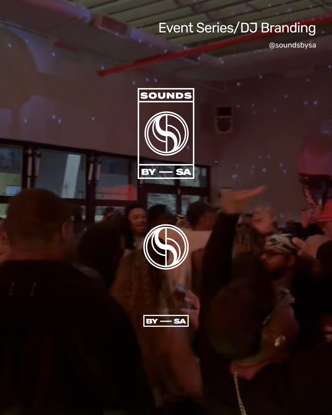 People dancing and socializing in a dimly lit indoor venue with a large screen displaying event branding.