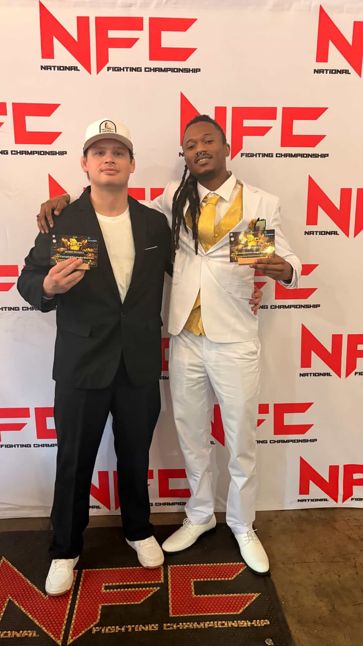 Two men standing in front of an NFC backdrop, holding awards and smiling.