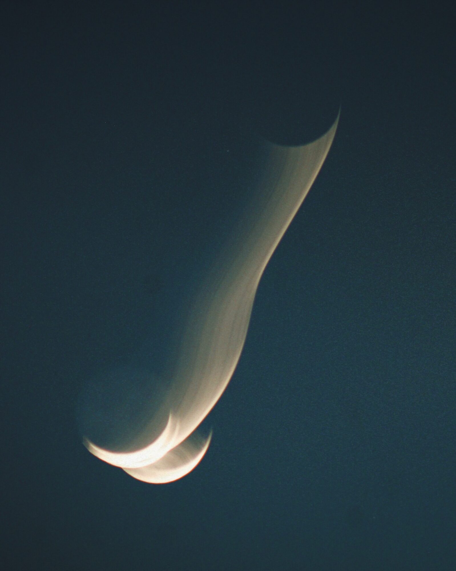 A bright meteor or fireball streaks through a dark sky with a glowing tail.