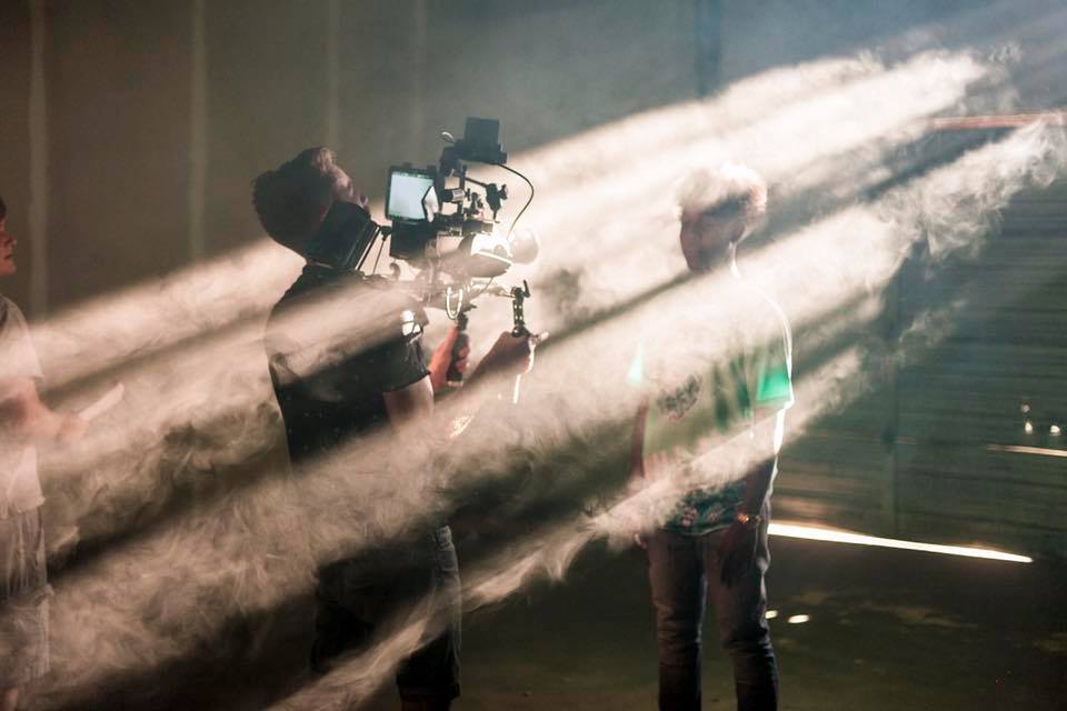 Photographer with camera and lighting equipment captures a scene with bright beams of light, partially obscuring the view.