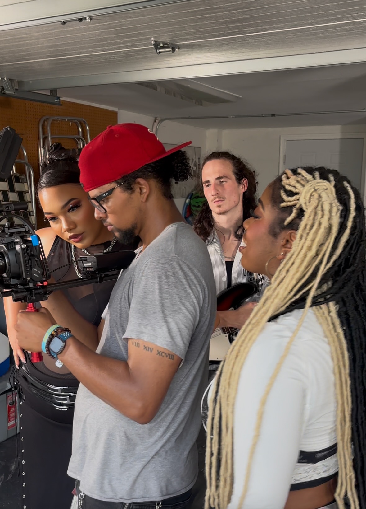 Four people in a room, one person holding a camera, others watching, with a ceiling and door visible.