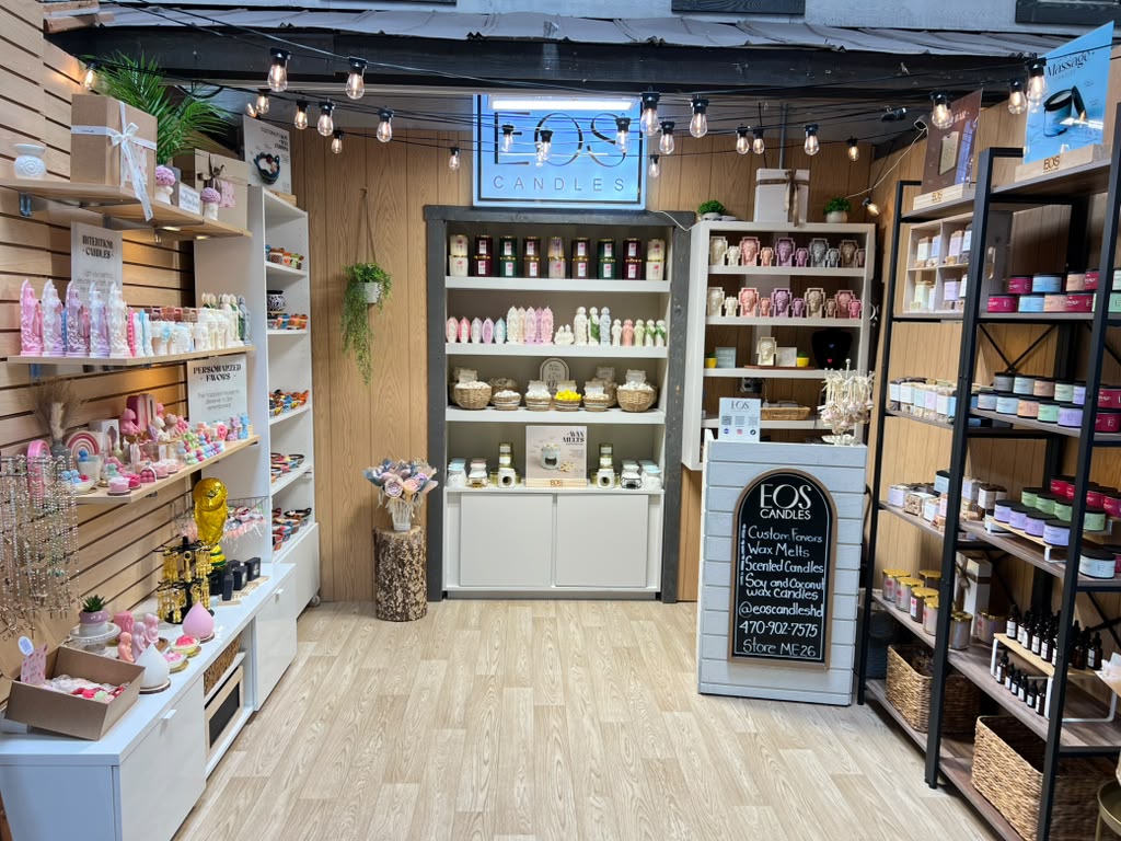 Interior of a store with shelves filled with colorful products, a chalkboard sign, and a wooden floor.