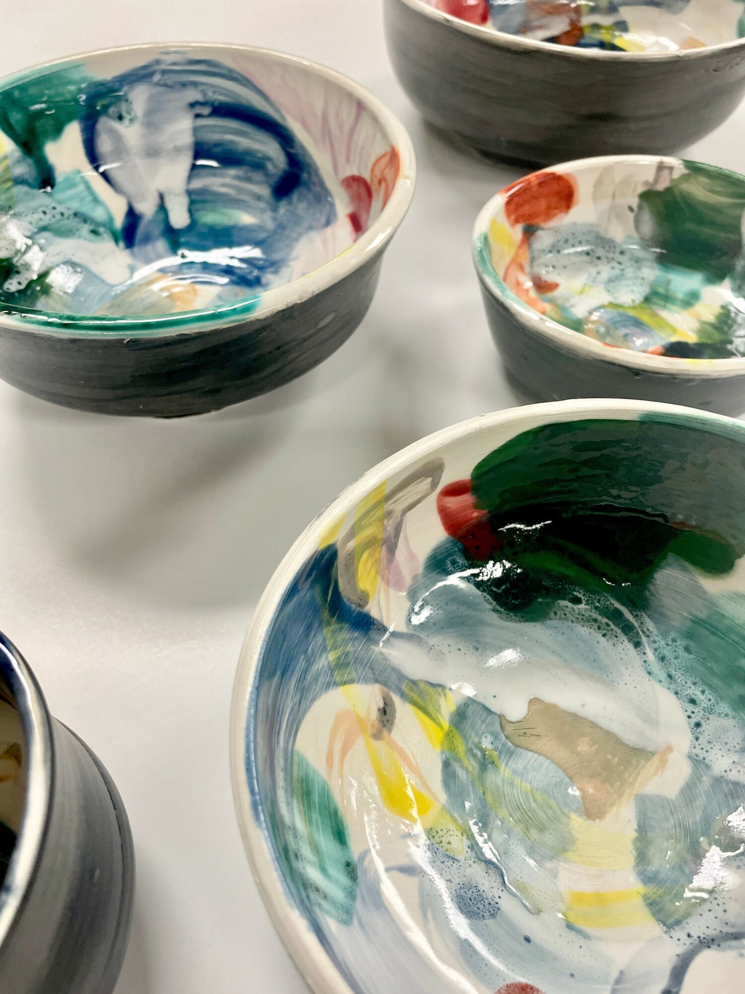 Colorful ceramic bowls with abstract paint patterns on a white surface.