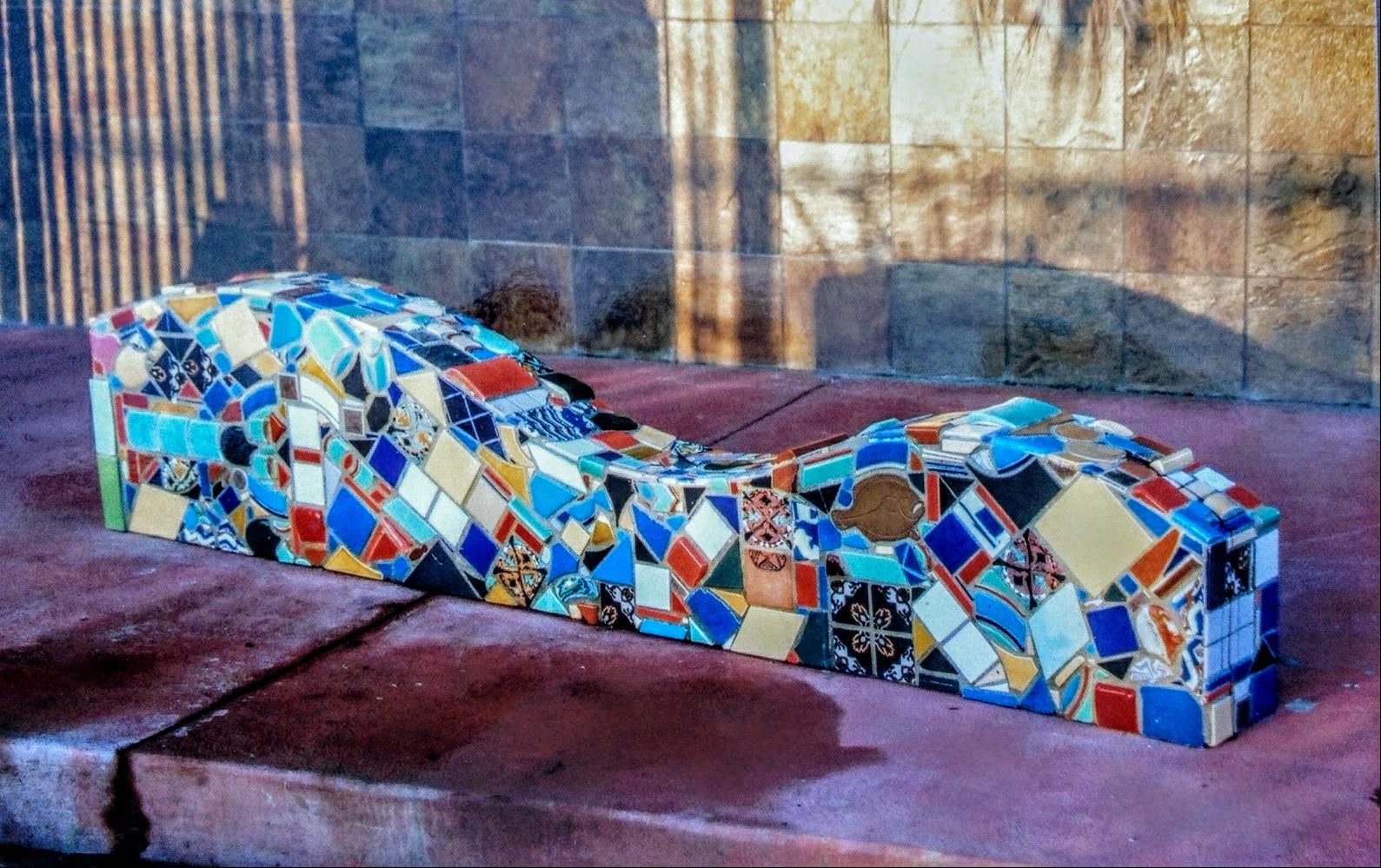 Colorful mosaic sculpture of a guitar resting on a stone surface.