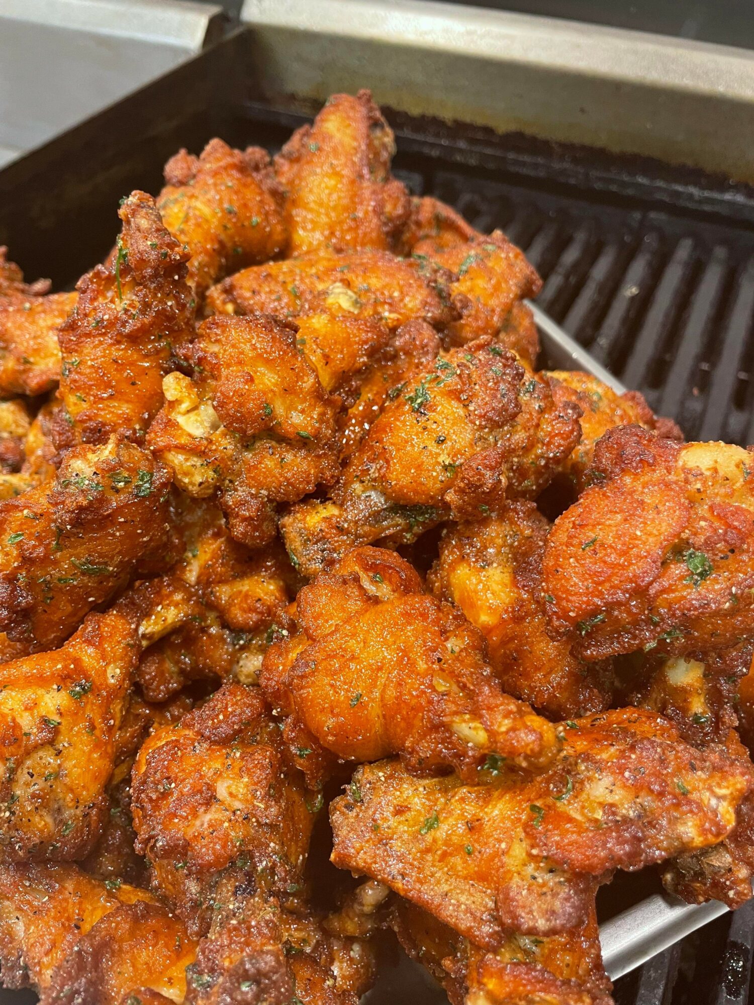 Close-up of crispy, fried chicken pieces with a golden-brown coating on a grill or tray.