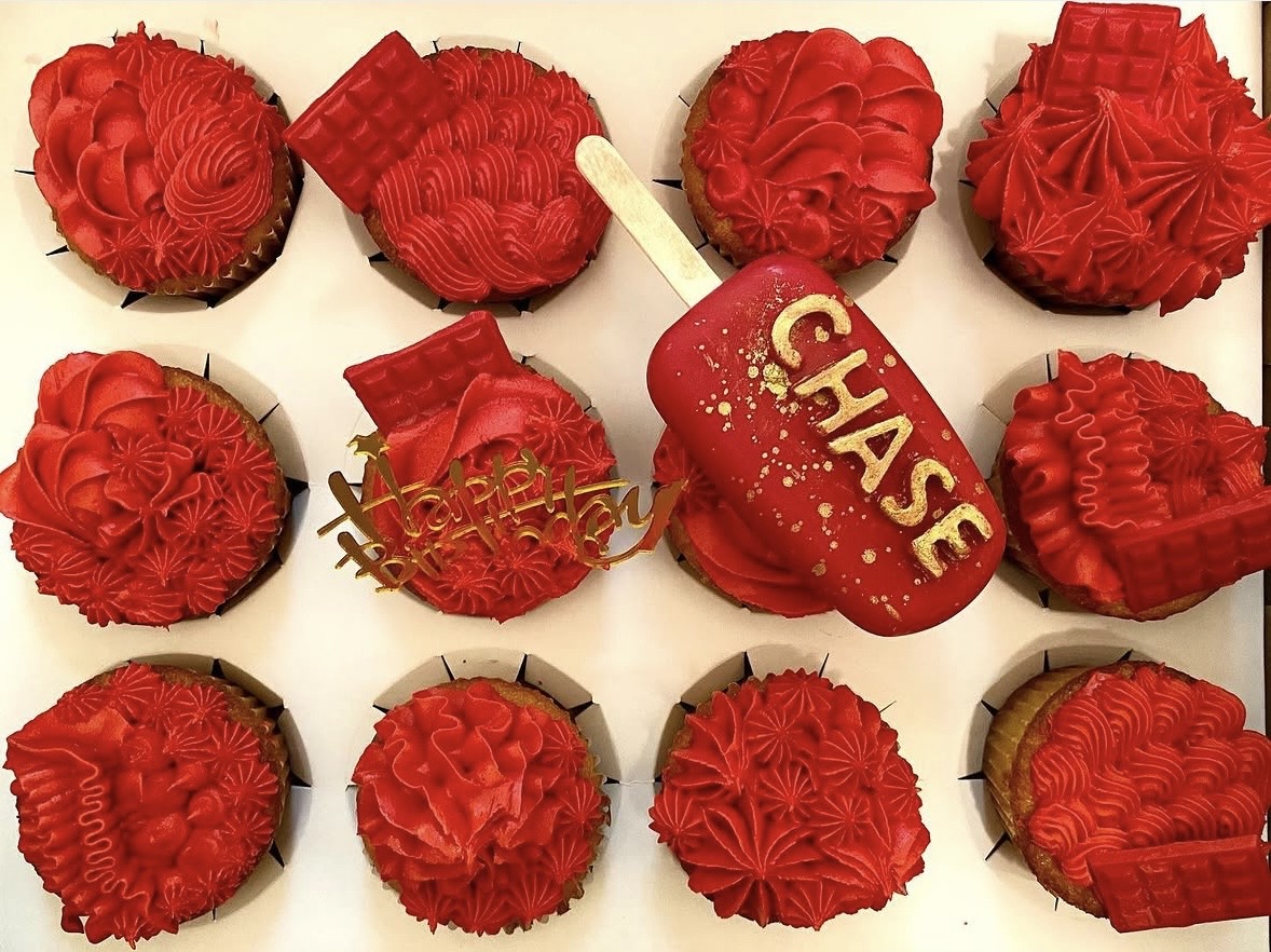 Nine red decorated cupcakes and a heart-shaped cake with a 'Chase' topper and a 'Happy Valentine's' sign, all on a white background.