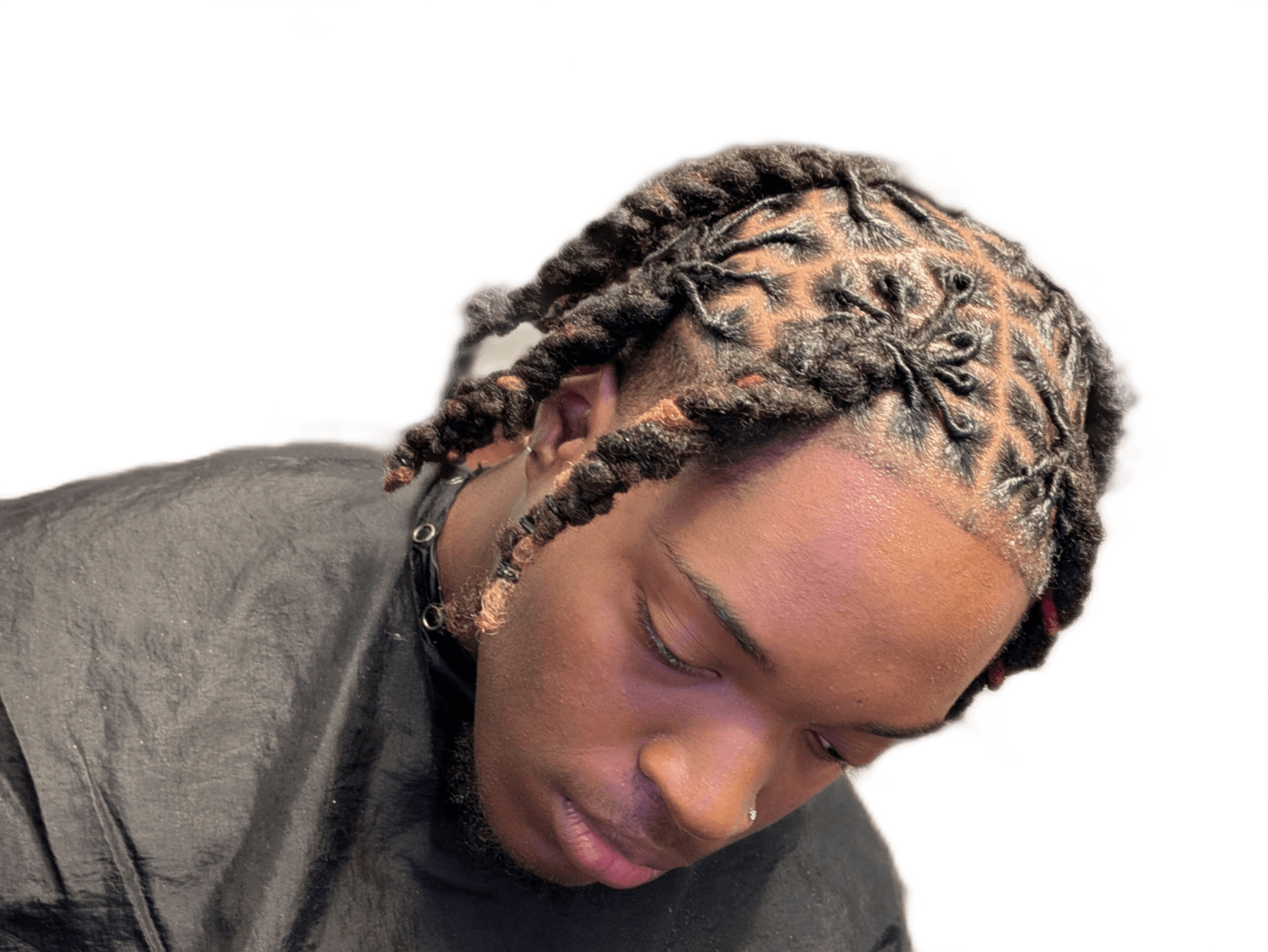 Young person with braided hair looking downward, wearing a dark shirt, against a black background.