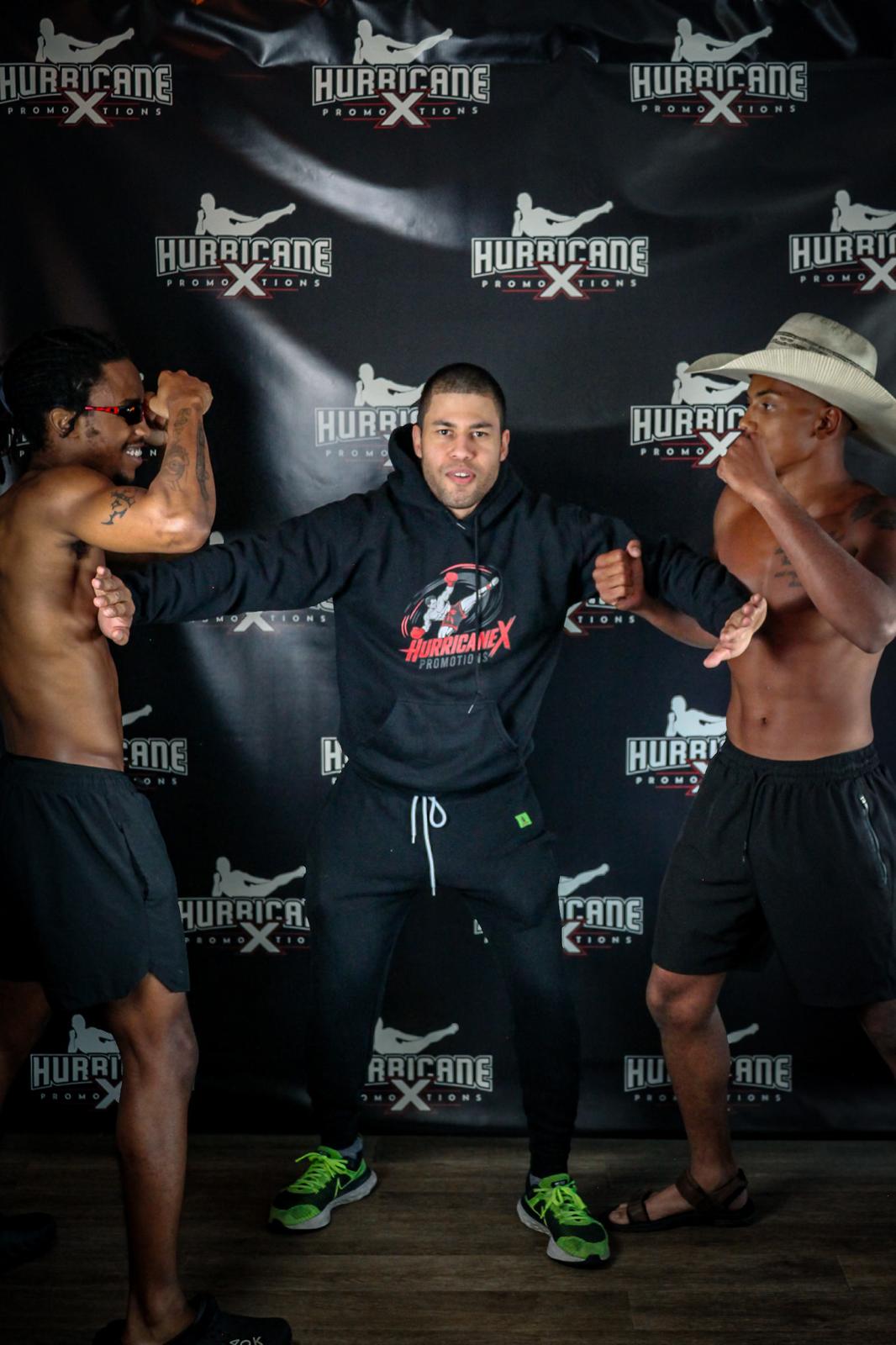 Three men in a fighting stance, two shirtless and one in a hoodie, in front of a black backdrop with 'HURRICANE' logos.