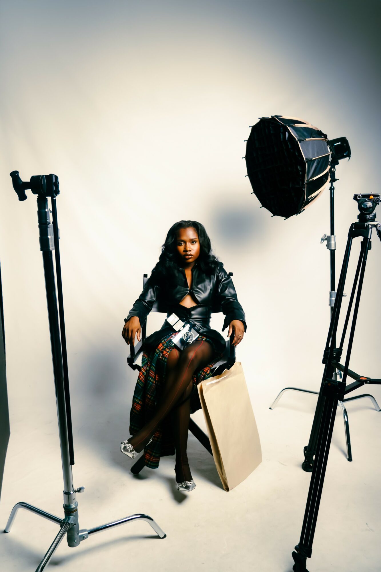 Woman sitting on a chair in a photography studio with lighting equipment around her.
