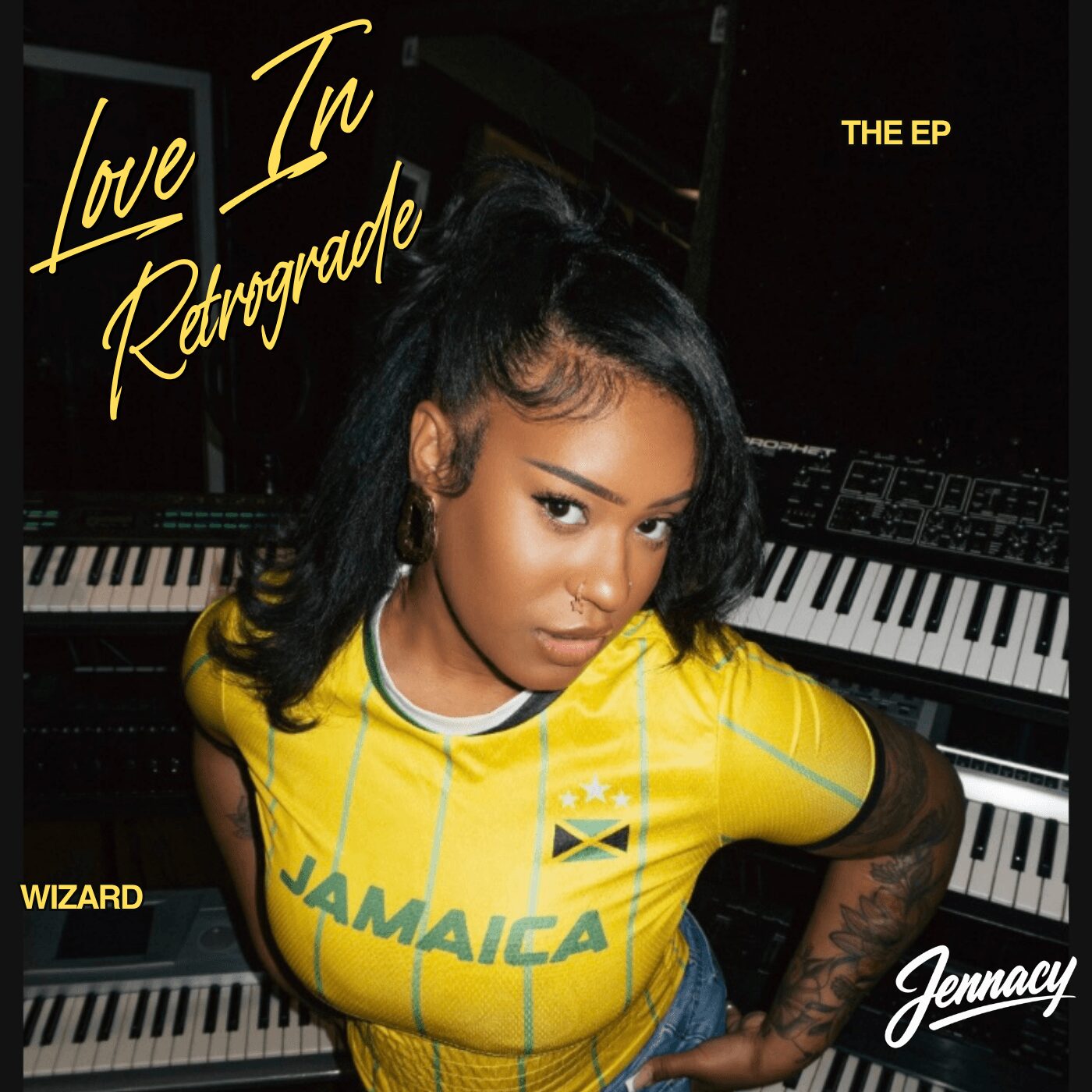 Young woman in yellow Jamaica shirt leaning on a piano, looking at the camera, with text about an EP titled Love In Retrograde.