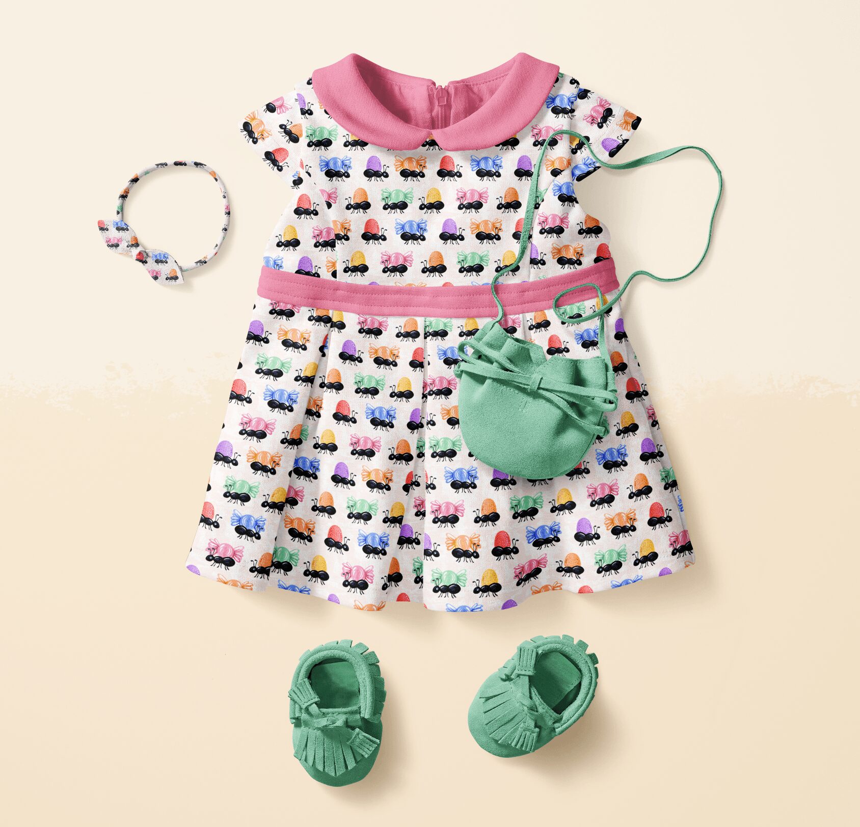 Child's dress with colorful cars, pink collar, green shoes, small green bag, and matching bracelet, arranged on a light background.
