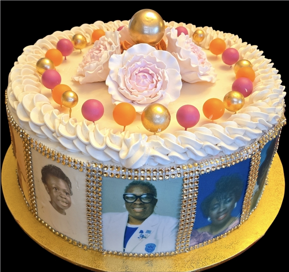 Decorative cake with photos of three women, colorful beads, and a large flower on top, on a gold base.