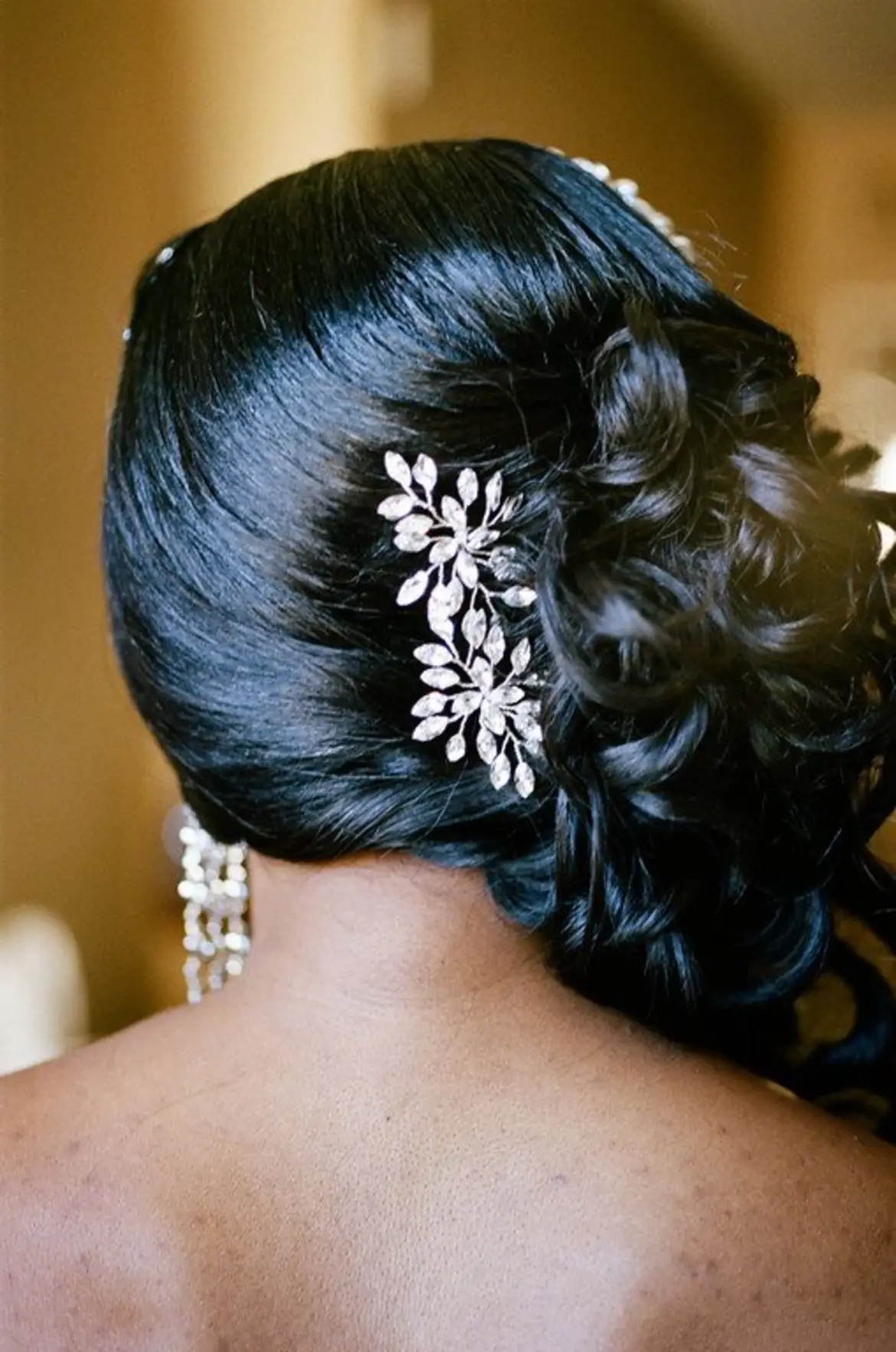 Back of a woman's head with styled black hair and decorative hair accessory, showing an elegant updo.