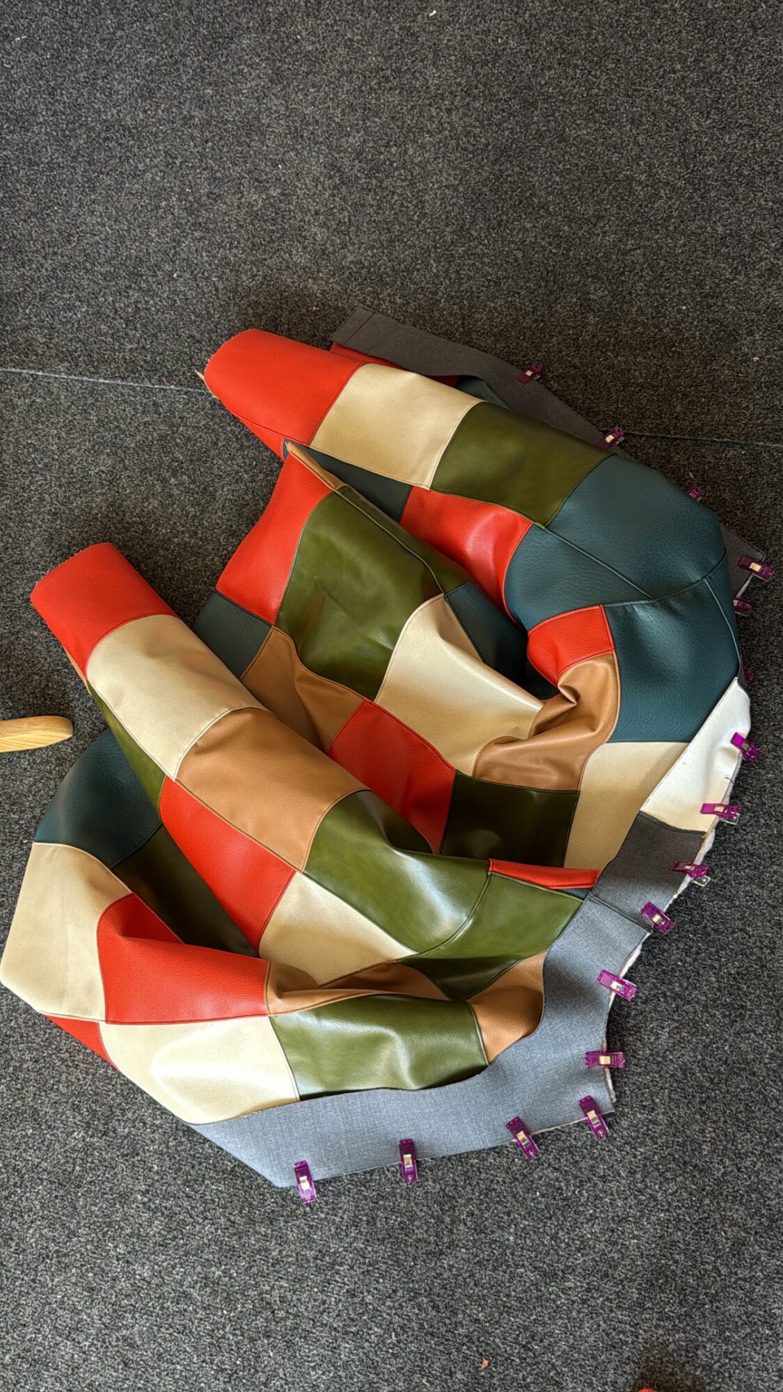 Colorful fabric with red, green, beige, and blue sections, partially folded on a dark surface.