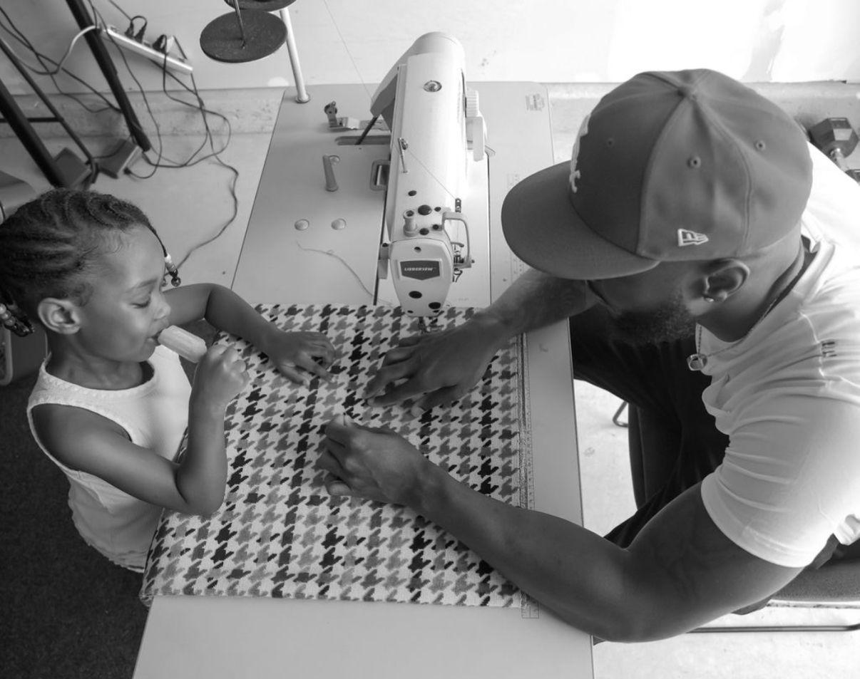 Adult and child working together on a sewing project at a table, with a sewing machine nearby.