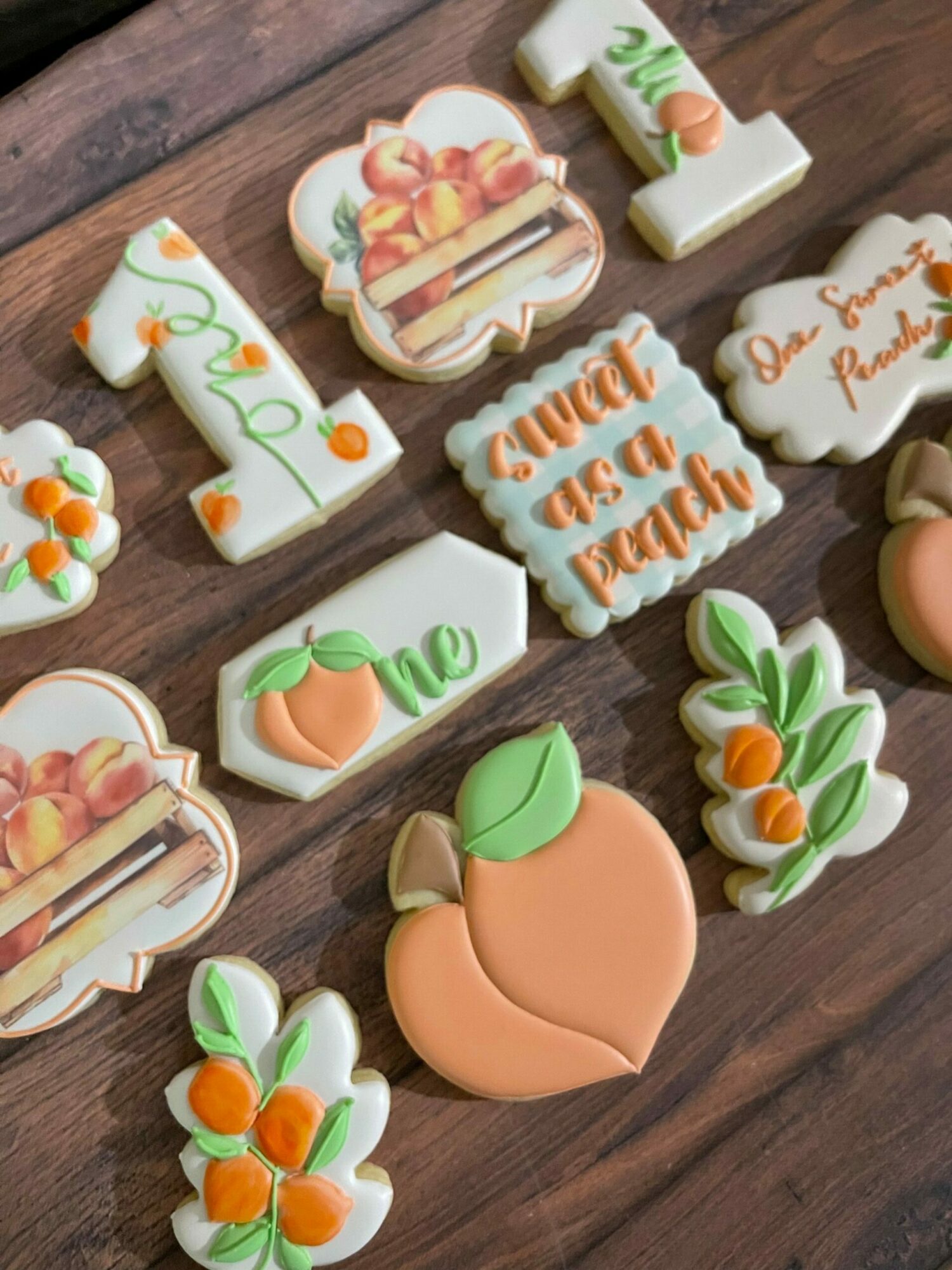 Assorted cookies with peach and leaf decorations on a wooden surface.