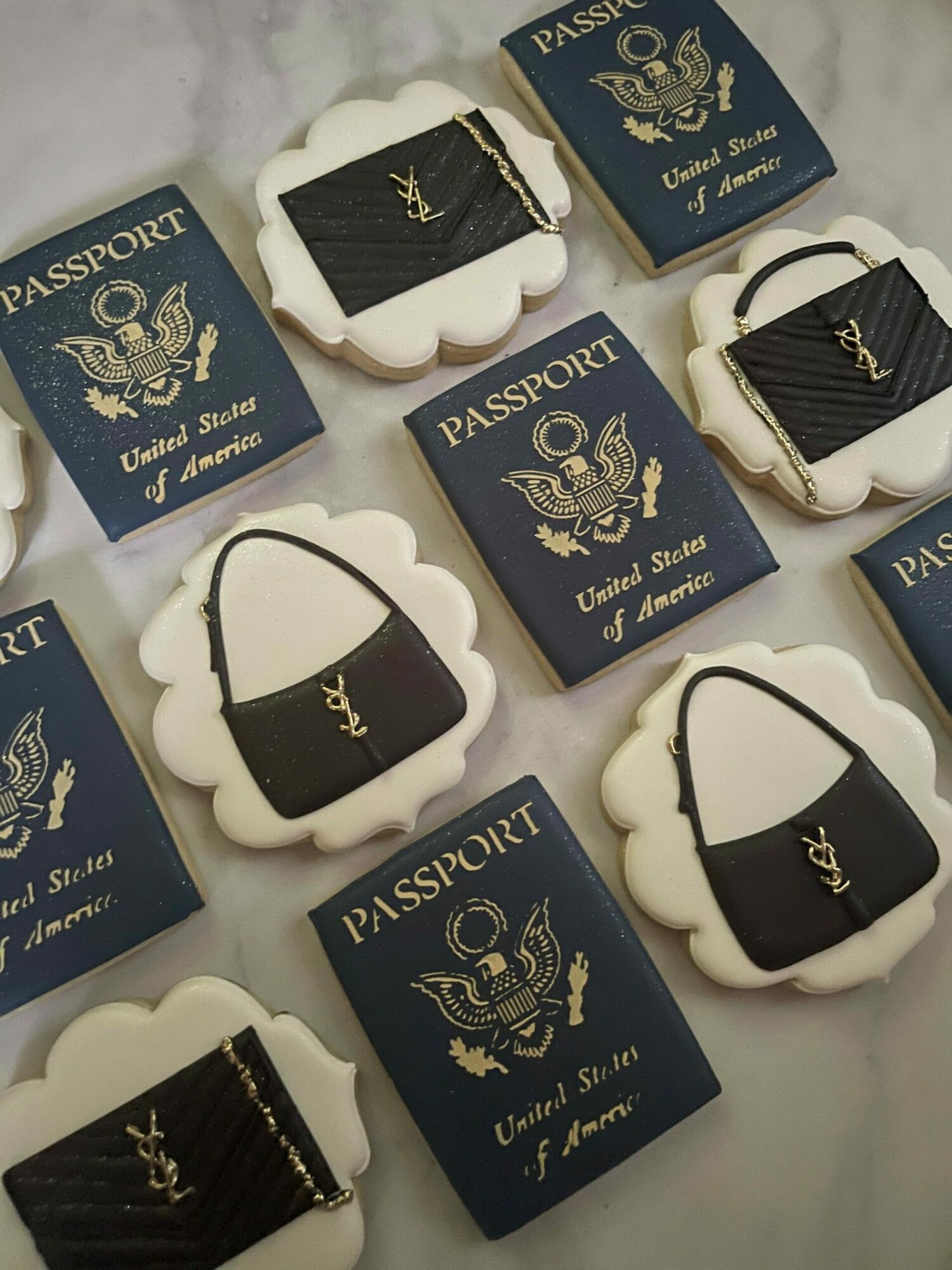 Cookies decorated with black and gold designs, placed on blue boxes with gold text and crest, on a light surface.
