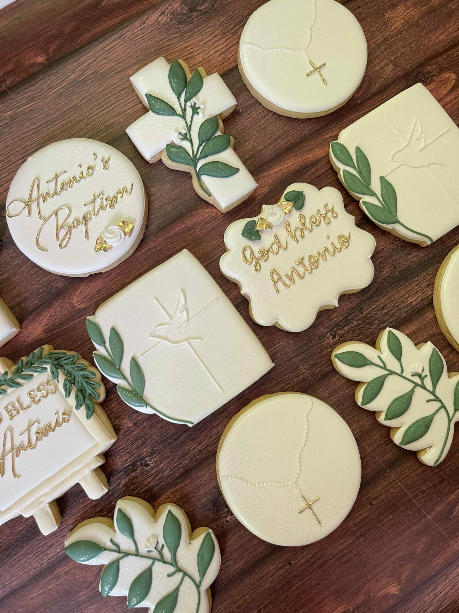 Decorative cookies with green leaf patterns and handwritten messages on a wooden surface.