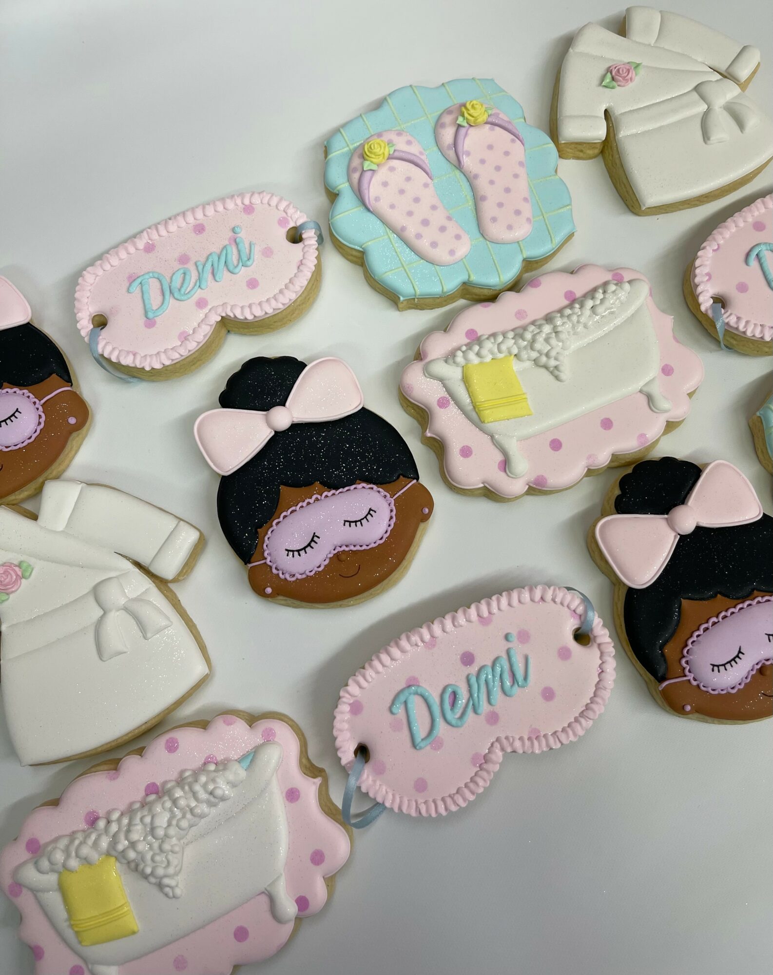 Decorated cookies with baby shower theme, including baby booties, a bathtub, and a girl with a bow, on a white surface.