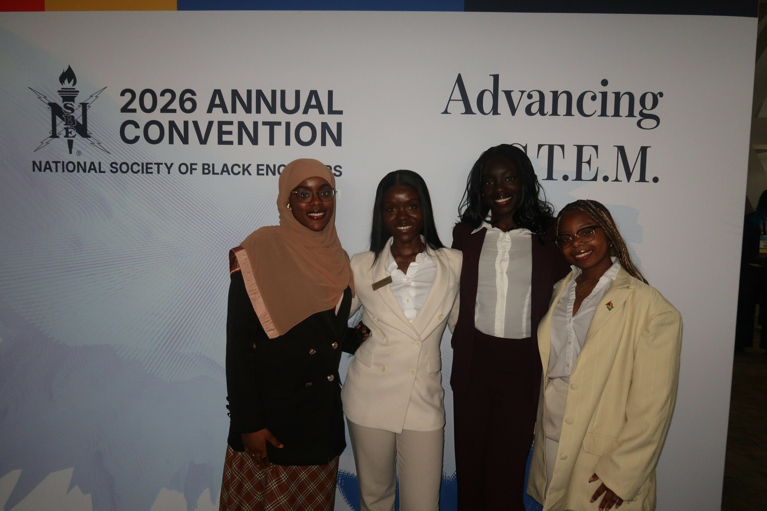 Four women standing together at a conference, smiling, with a banner in the background reading '2026 Annual Convention' and 'Advancing T.E.M.'