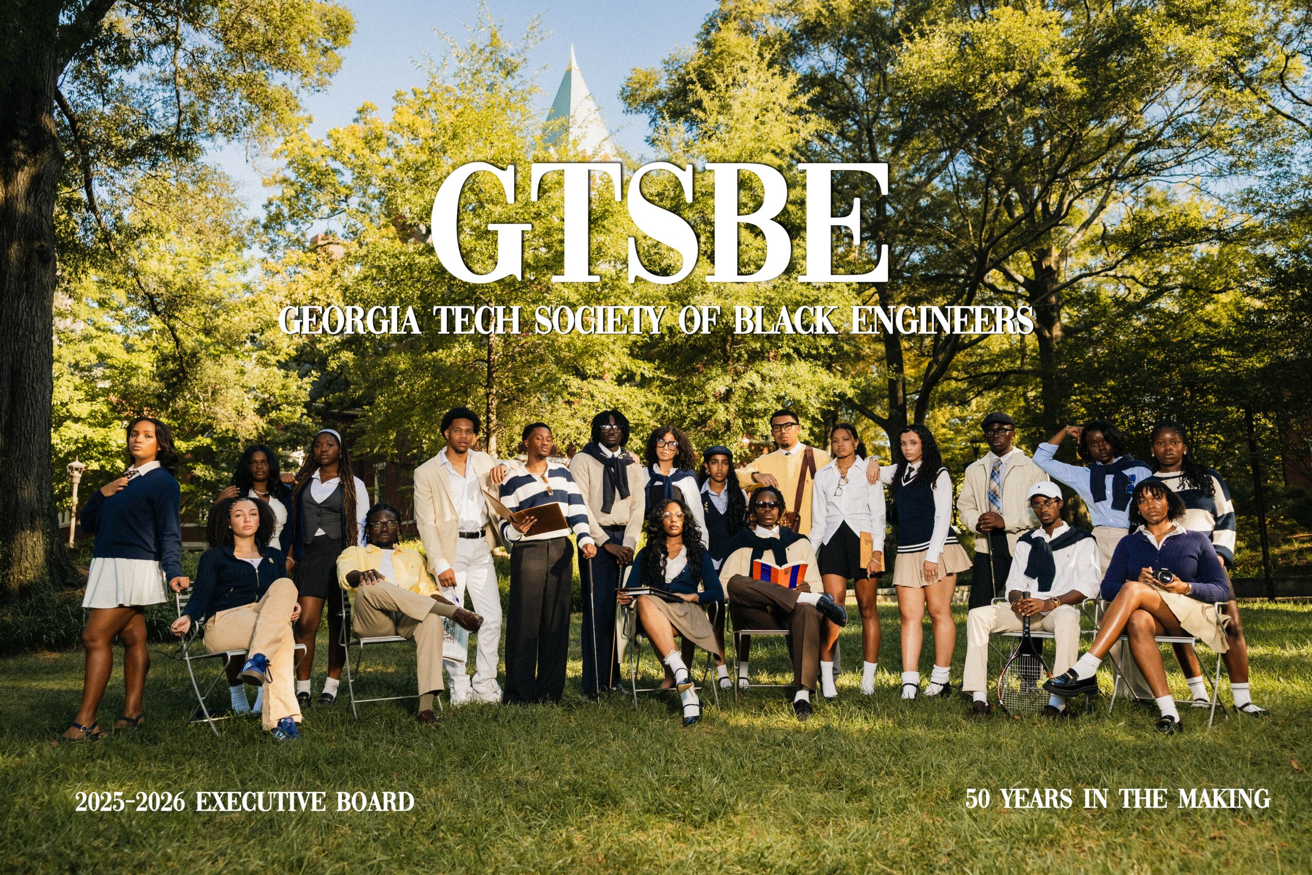 Group of students outdoors on grass with trees and a monument in background, posing for a photo, Georgia Tech logo visible.